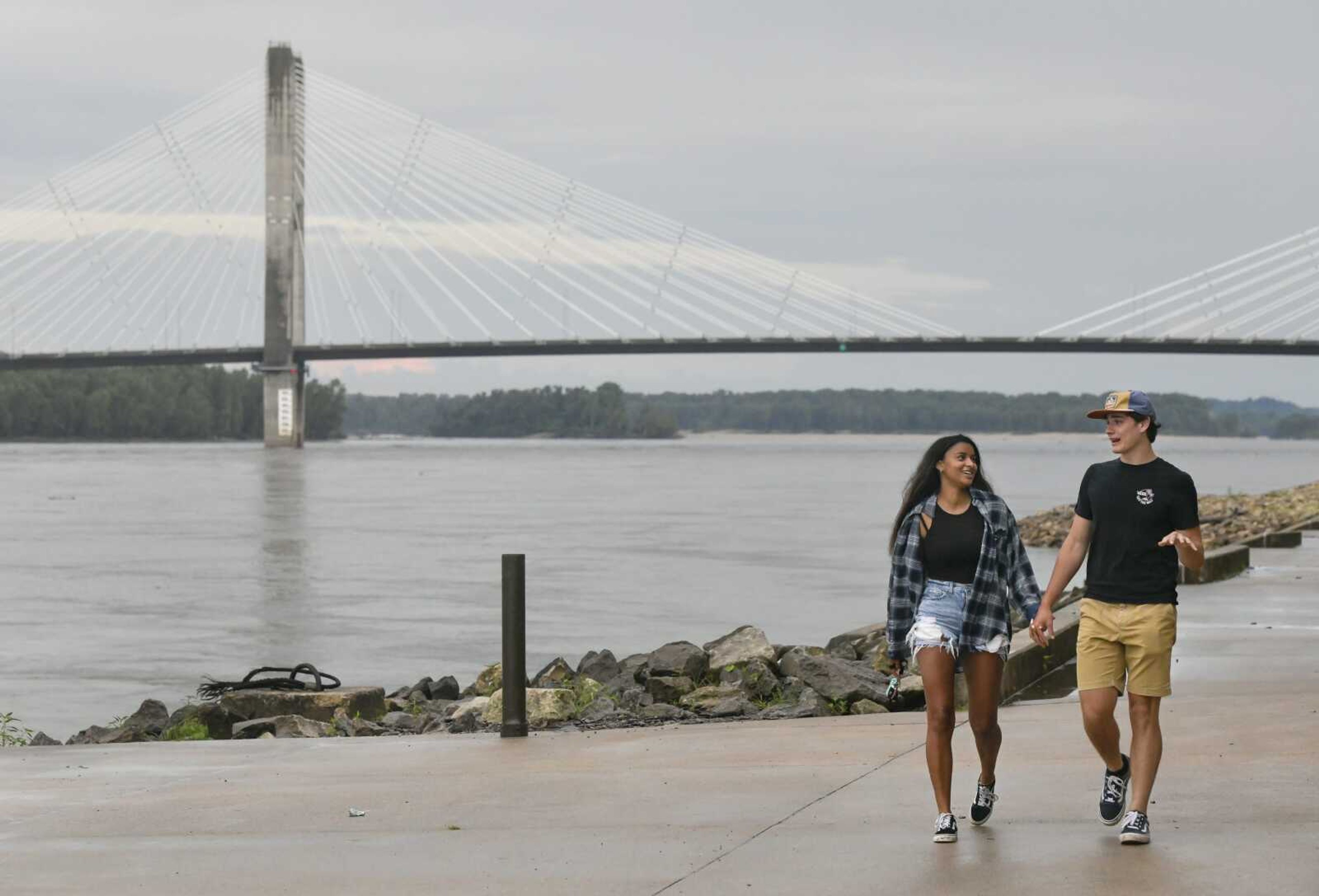 Aisha Rupert, 18, and Braden Hudgins, 17, both of Carbondale, Illinois, hold hands while walking along the Mississippi River after a rainstorm Sunday at Riverfront Park in Cape Girardeau.