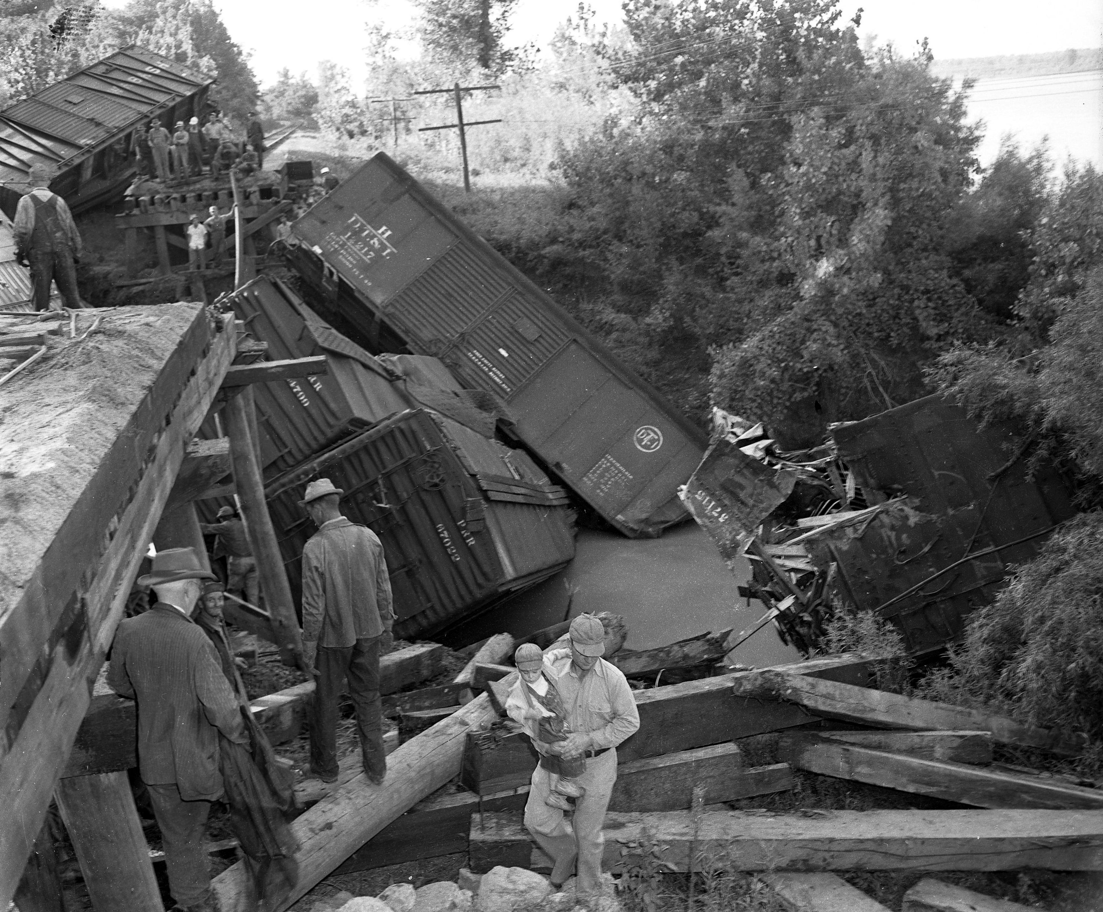 The curious view the twisted remains of a Frisco freight train that derailed near Seventy-Six on Sept. 12, 1949. At left can be seen the 140-foot gap caused by the collapse of a trestle into a flooded creek. Three trainmen lost their lives in the accident.