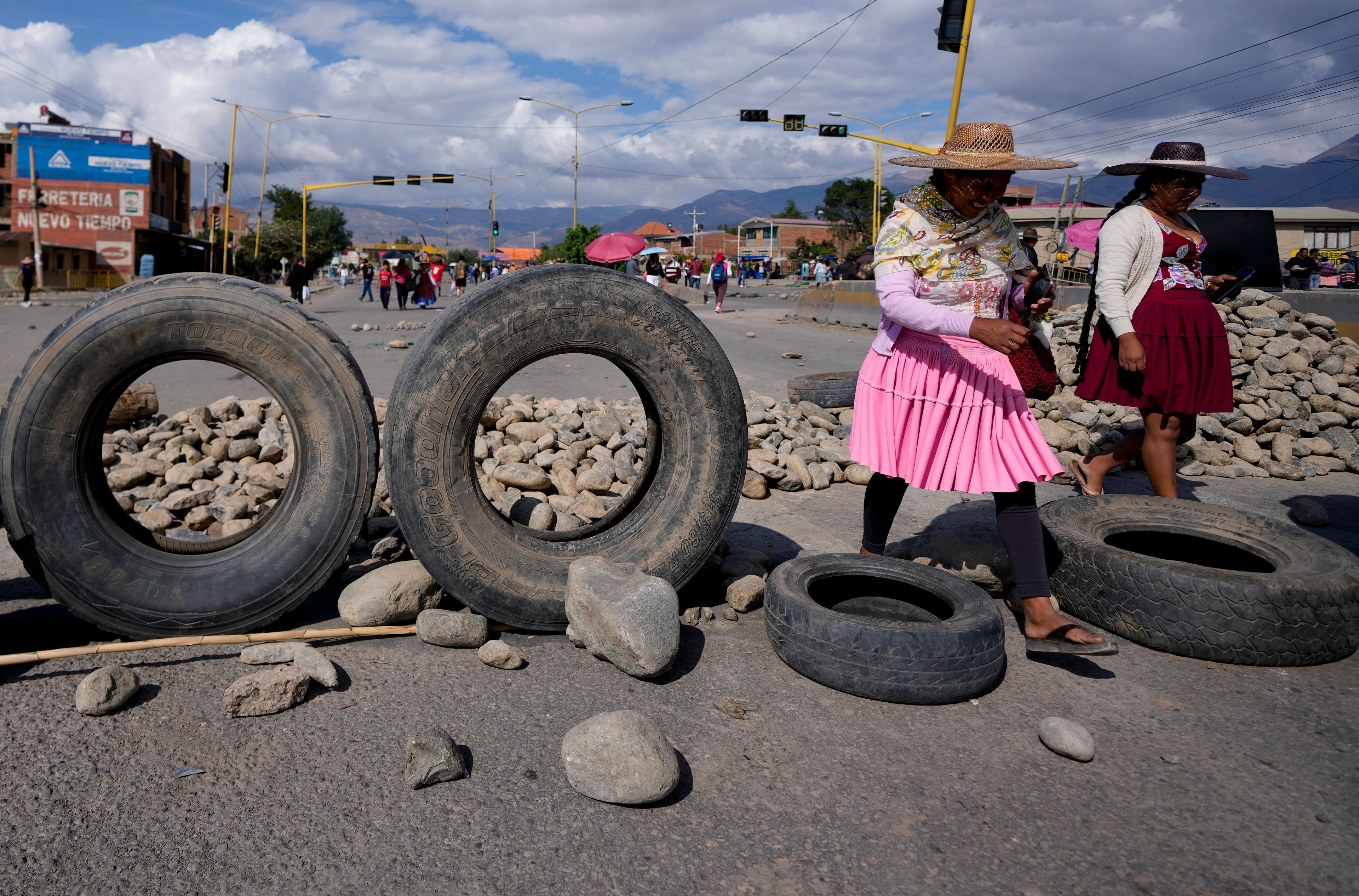 Women walk past a barricade of debris set up by supporters of former President Evo Morales who are blocking roads to prevent him from facing a criminal investigation over allegations of abuse of a minor and to protest an alleged assassination attempt near Cochabamba, Bolivia, Monday, Oct. 28, 2024. (AP Photo/Juan Karita)