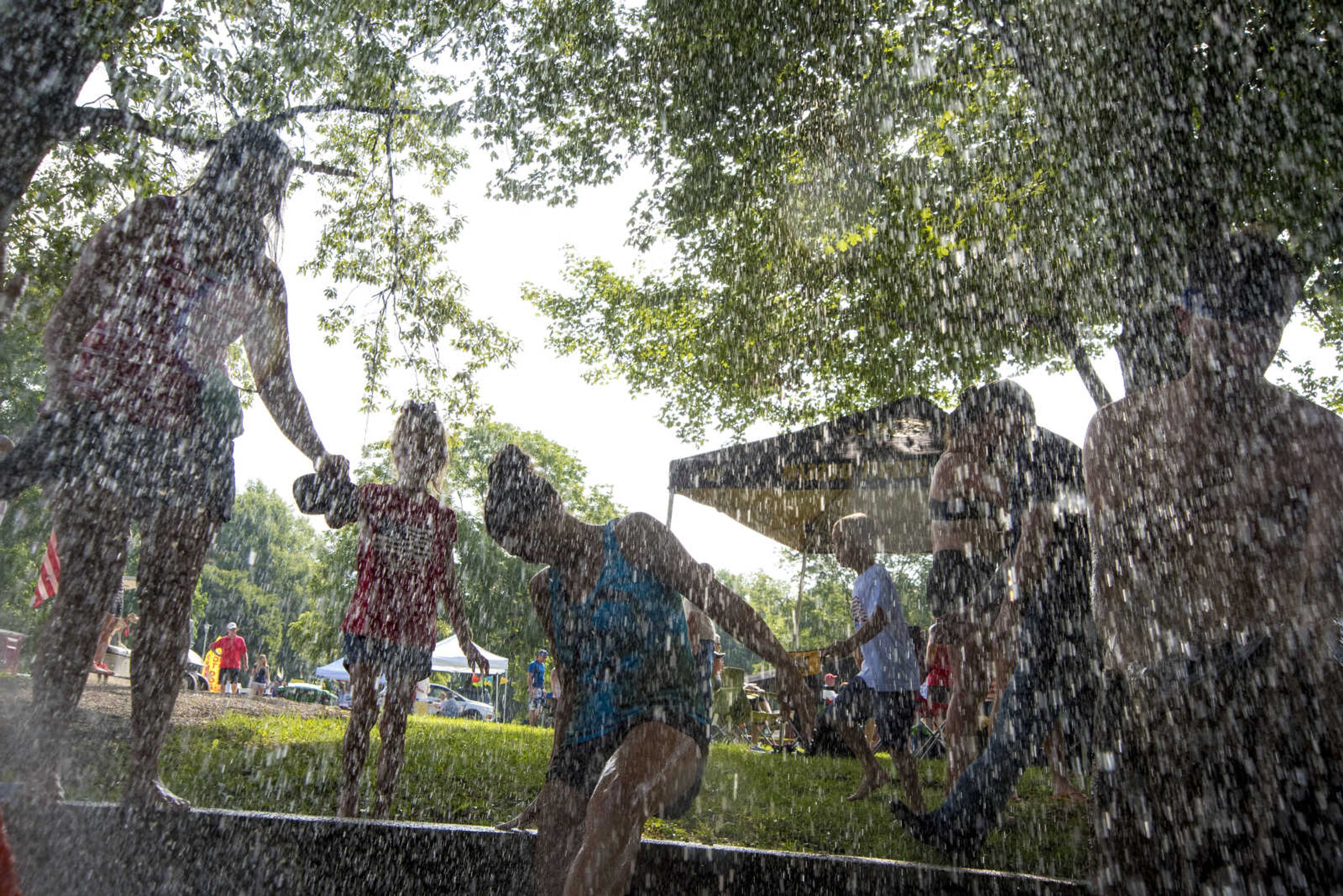 People wash off after playing mud volleyball for the Jackson Parks and Recreation's July 4th celebration Tuesday, July 4, 2017 in Jackson City Park.