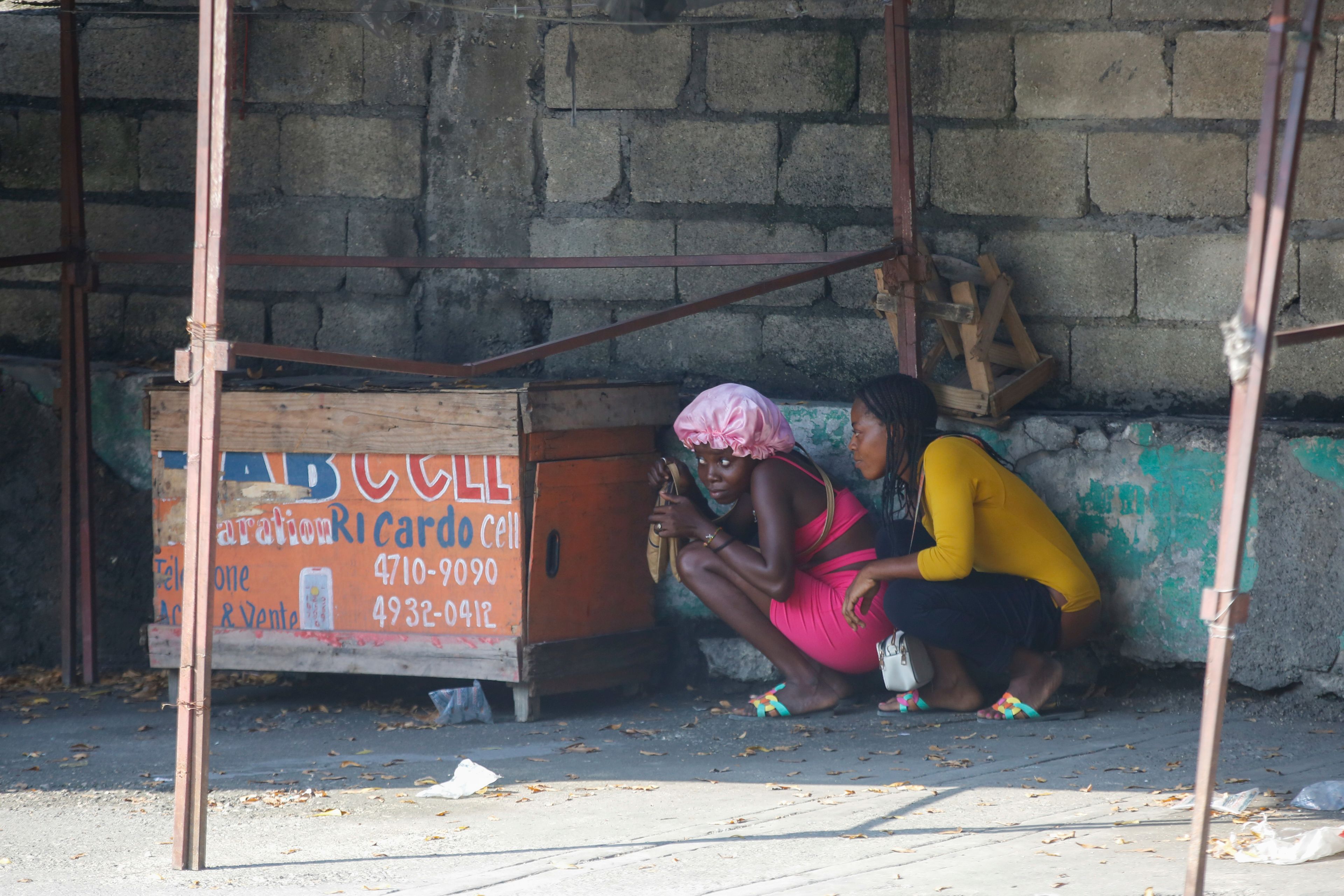 FILE - Women take cover during a gun battle between police and gang members in Port-au-Prince, Haiti, March 1, 2024. (AP Photo/Odelyn Joseph, File)