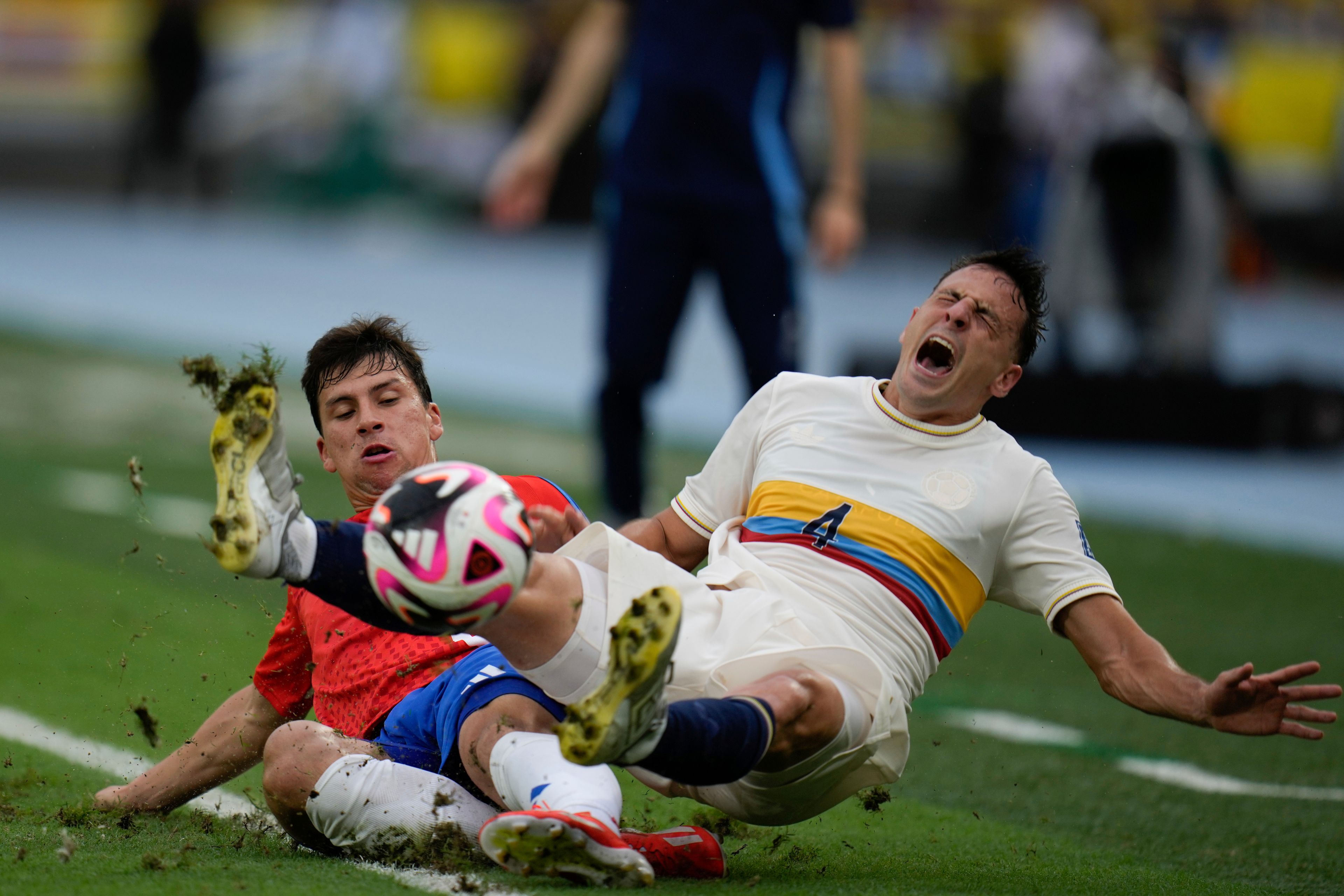 Colombia's Santiago Arias, right, and Chile's Gonzalo Tapia fall during a FIFA World Cup 2026 qualifying soccer match at the Metropolitano Roberto Melendez stadium in Barranquilla, Colombia, Oct. 15, 2024. (AP Photo/Fernando Vergara)