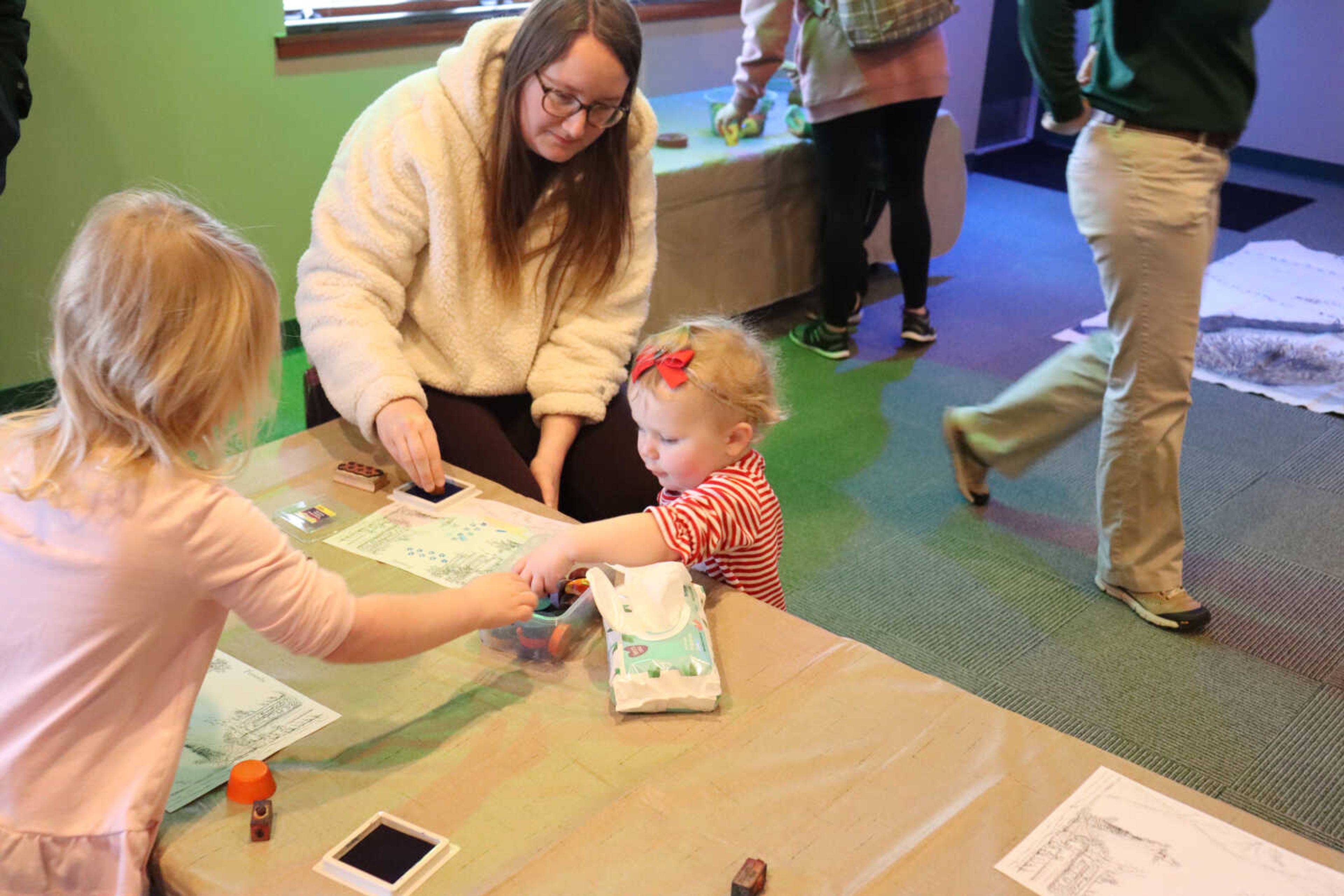 (Left) Lucan tries along with her mother to help out her sibling Lena with filling out her coloring page.