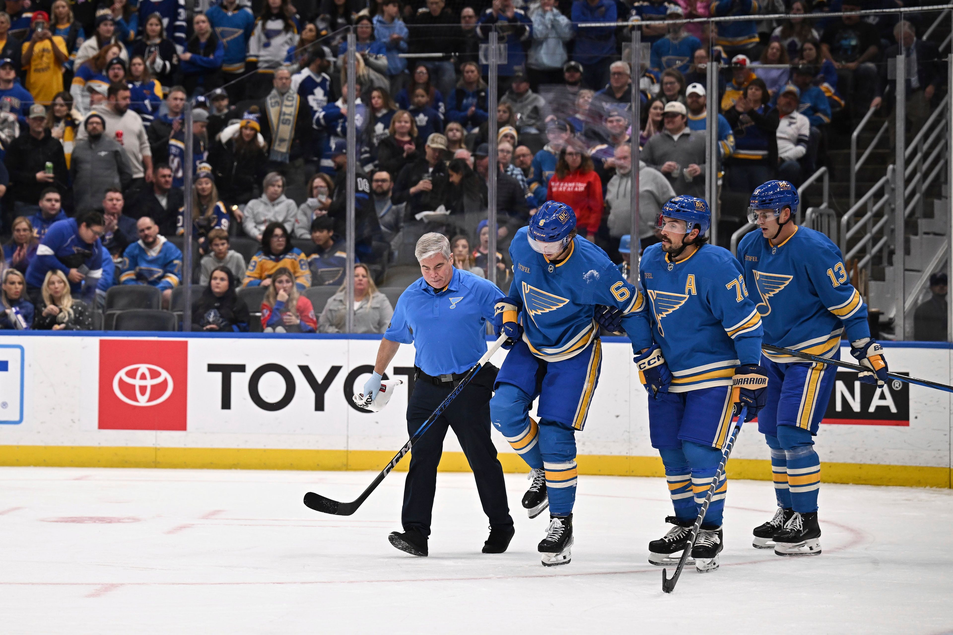 St. Louis Blues' Philip Broberg (6) is assisted off the ice by teammates during the second period of an NHL hockey game against the Toronto Maple Leafs, Saturday, Nov. 2, 2024, in St. Louis. (AP Photo/Connor Hamilton)