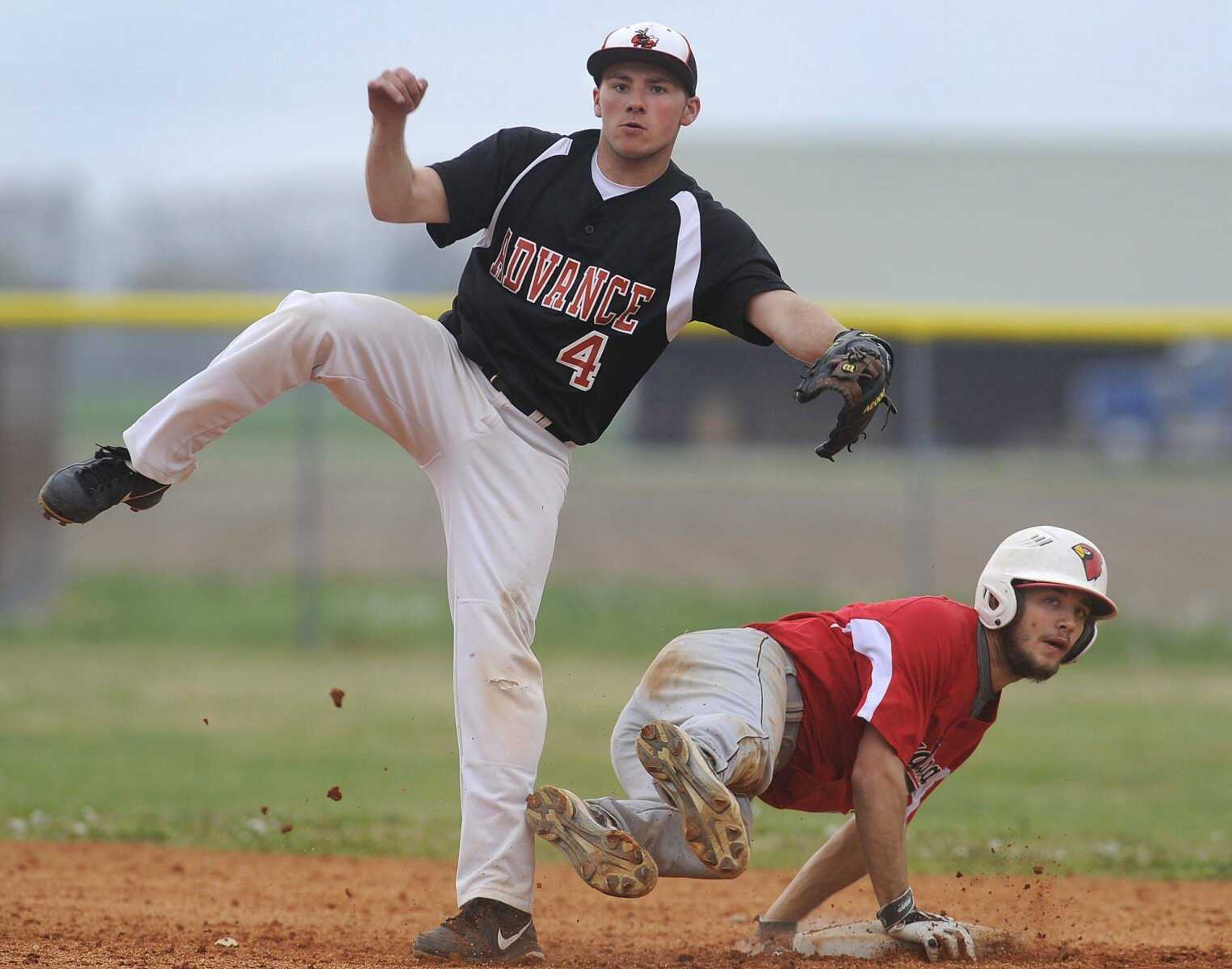 Advance second baseman Austin Miller watches his throw to first base along with Woodland&#8217;s Devon Ritter as he completes a double play during the seventh inning Monday in Advance, Mo. The Hornets advanced to the semifinals of the Stoddard County Activities Association tournament with a 2-0 victory. (Fred Lynch)