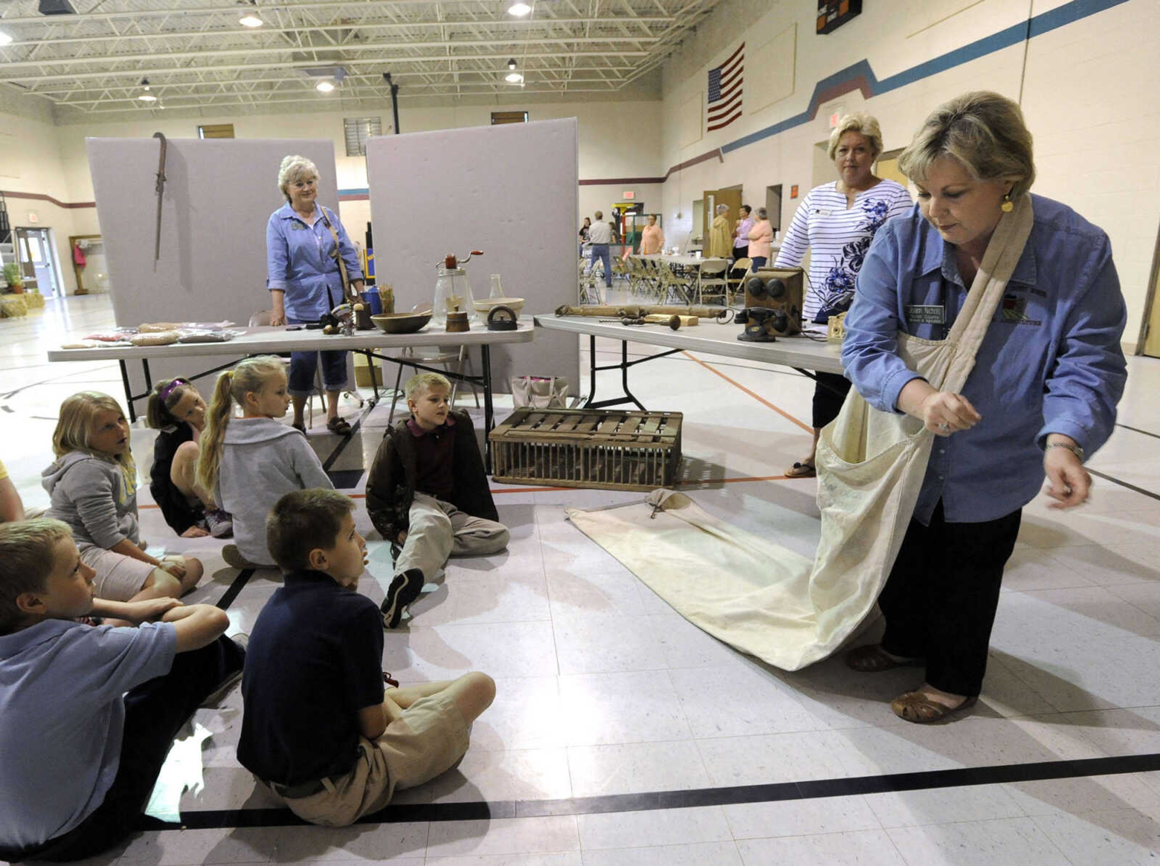 Joann Nicholls, a member of the Scott County Women in Agriculture, shows a cotton sack to students of St. Ambrose School at Farm Day.