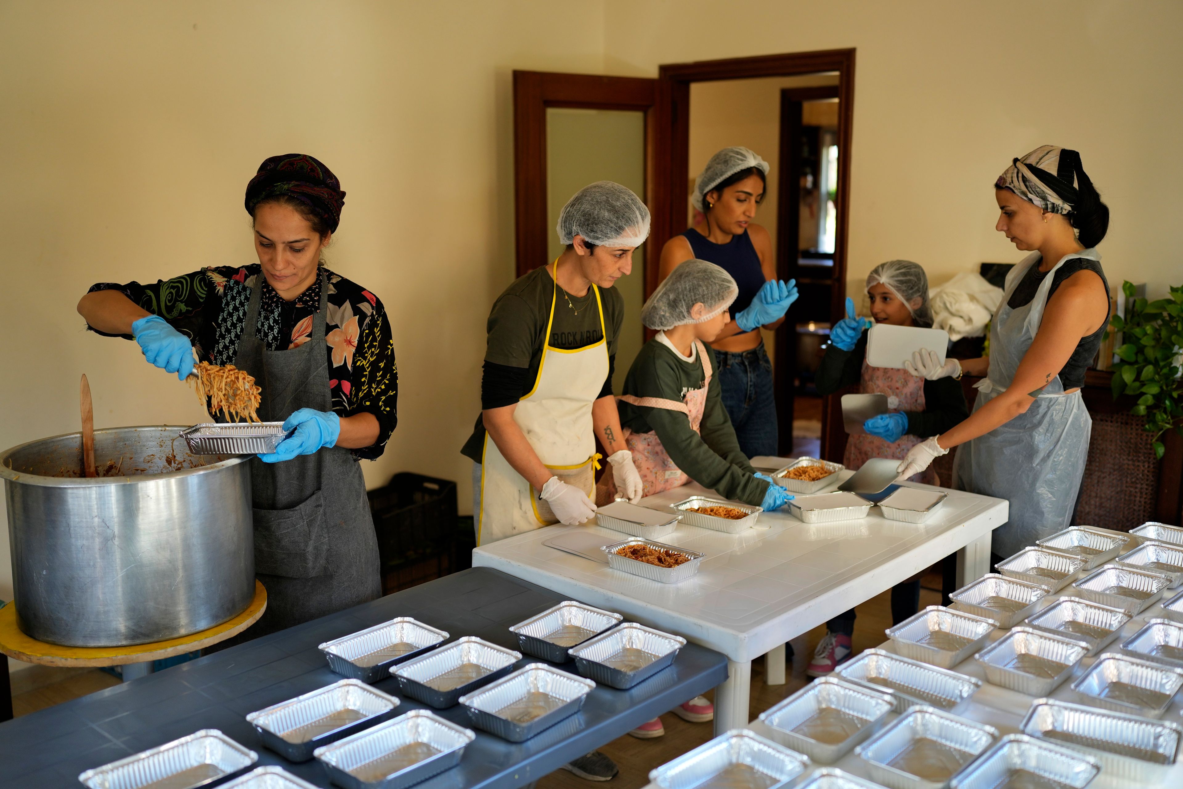 Volunteers prepare meals at a women's art center that was turned into a kitchen for displaced people who fled southern Lebanon amid the ongoing Hezbollah-Israel war, in the town of Aqaibe, northern Lebanon, Thursday, Oct. 24, 2024. (AP Photo/Hassan Ammar)