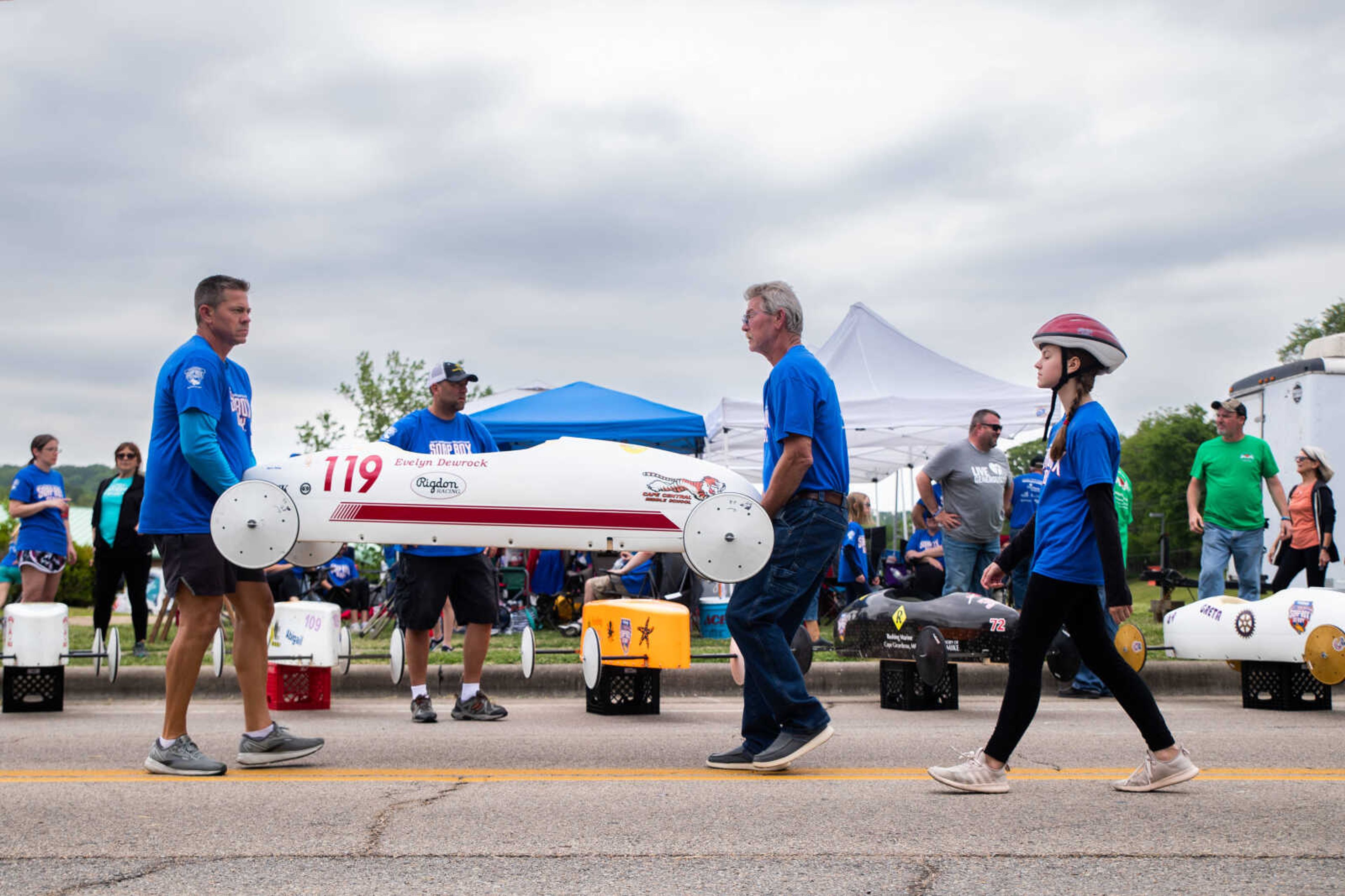 Evelyn Dewrock walks behind her car as her racing team carries it to the starting line of the Soap Box Derby on Saturday, May 6 at Blanchard Elementary School.