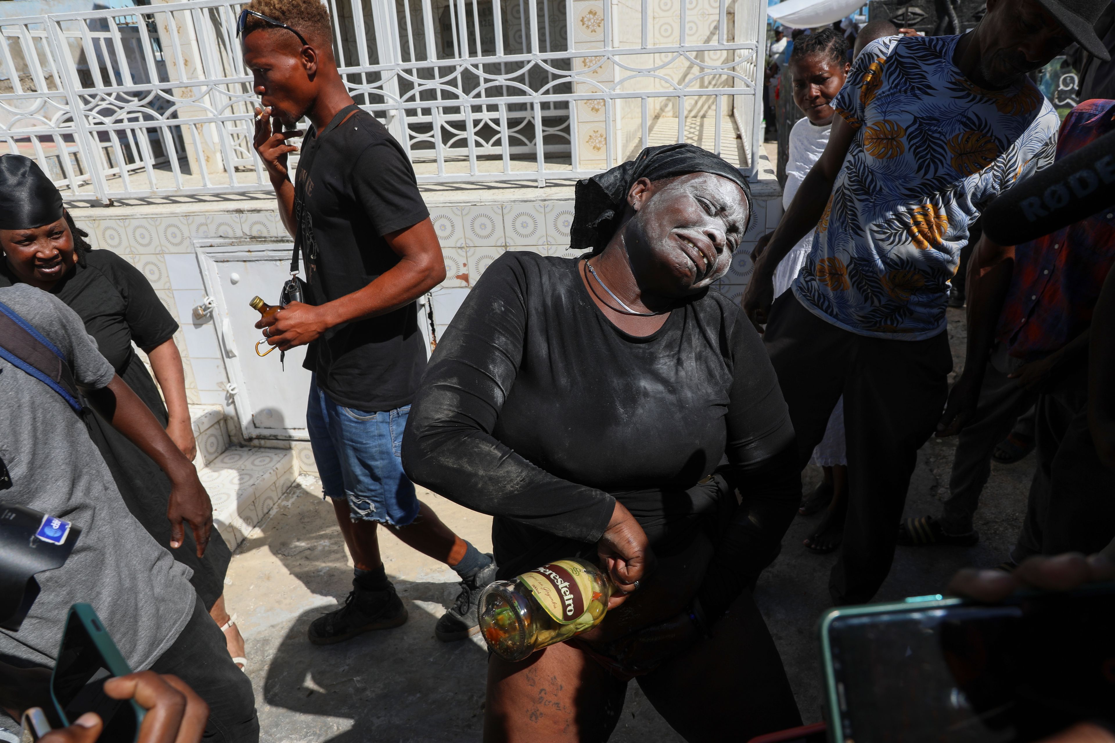 A Vodou believer pours homemade alcohol spiced with hot pepper on herself during the annual Fete Gede festival that celebrates Day of the Dead, honoring the Haitian spirits Baron Samedi and Gede, at the National Cemetery, in Port-au-Prince, Haiti, Friday, Nov. 1, 2024. (AP Photo/Odelyn Joseph)