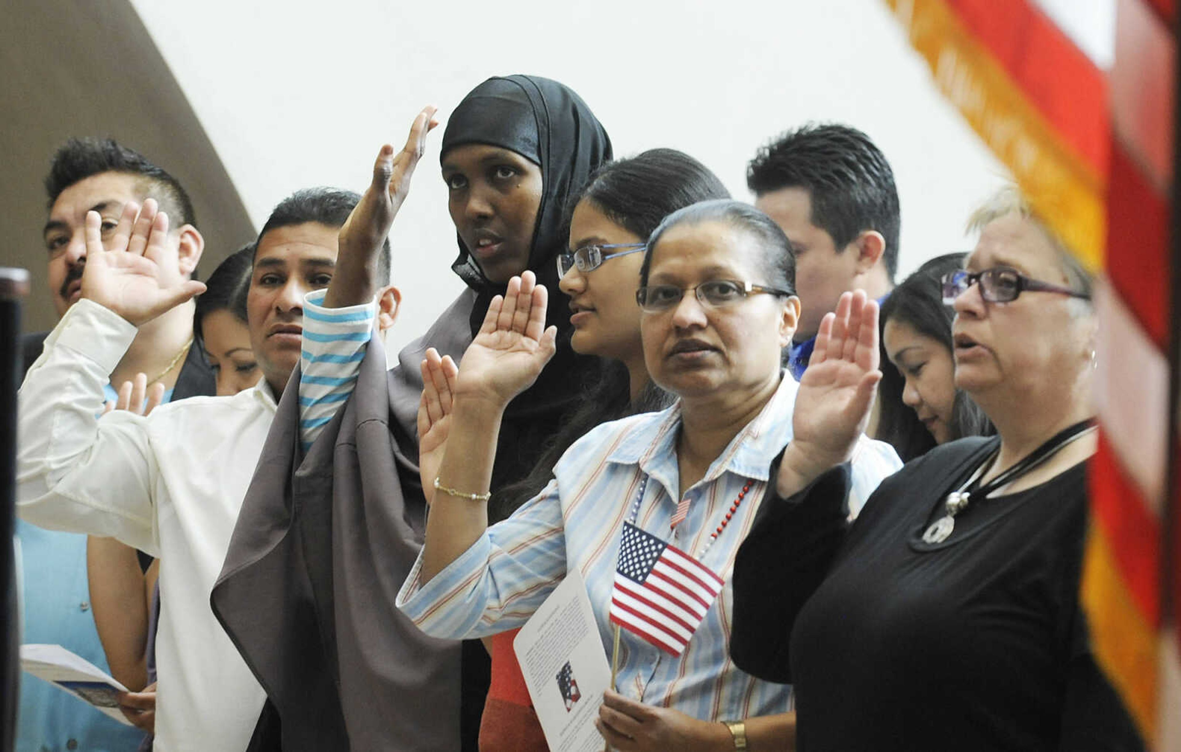 Immigrants raise their right hands to take the Oath of Allegiance during a naturalization ceremony Wednesday, May 1, at the Rush H. Limbaugh Sr. U.S. Courthouse in Cape Girardeau. U.S. District Court Judge Stephen N. Limbaugh Jr. administered the oath to 29 people from 11 countries, making them U.S. citizens, during the ceremony.