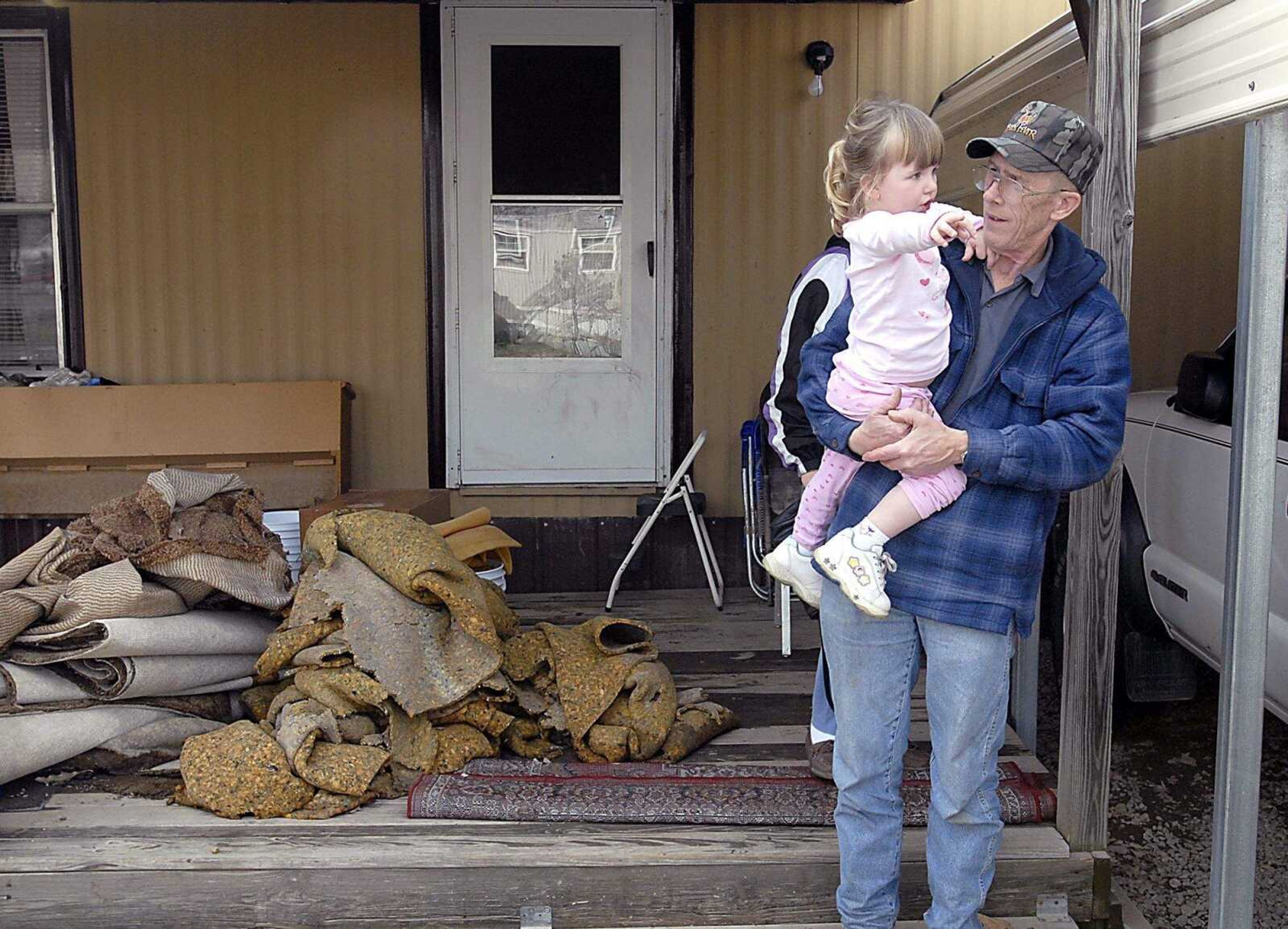 KIT DOYLE ~ kdoyle@semissourian.com
Gerald Sebastian saw his granddaughter, Kaylee Williams, 2, Friday, March 21, 2008, for the first time since she and the rest of the family was evacuated Wednesday from their Allenville home. Sebastian, who stayed in Allenville through the flooding, tore out the home's ruined carpets , left, earlier Friday. The Sebastians had about six inches in their home.