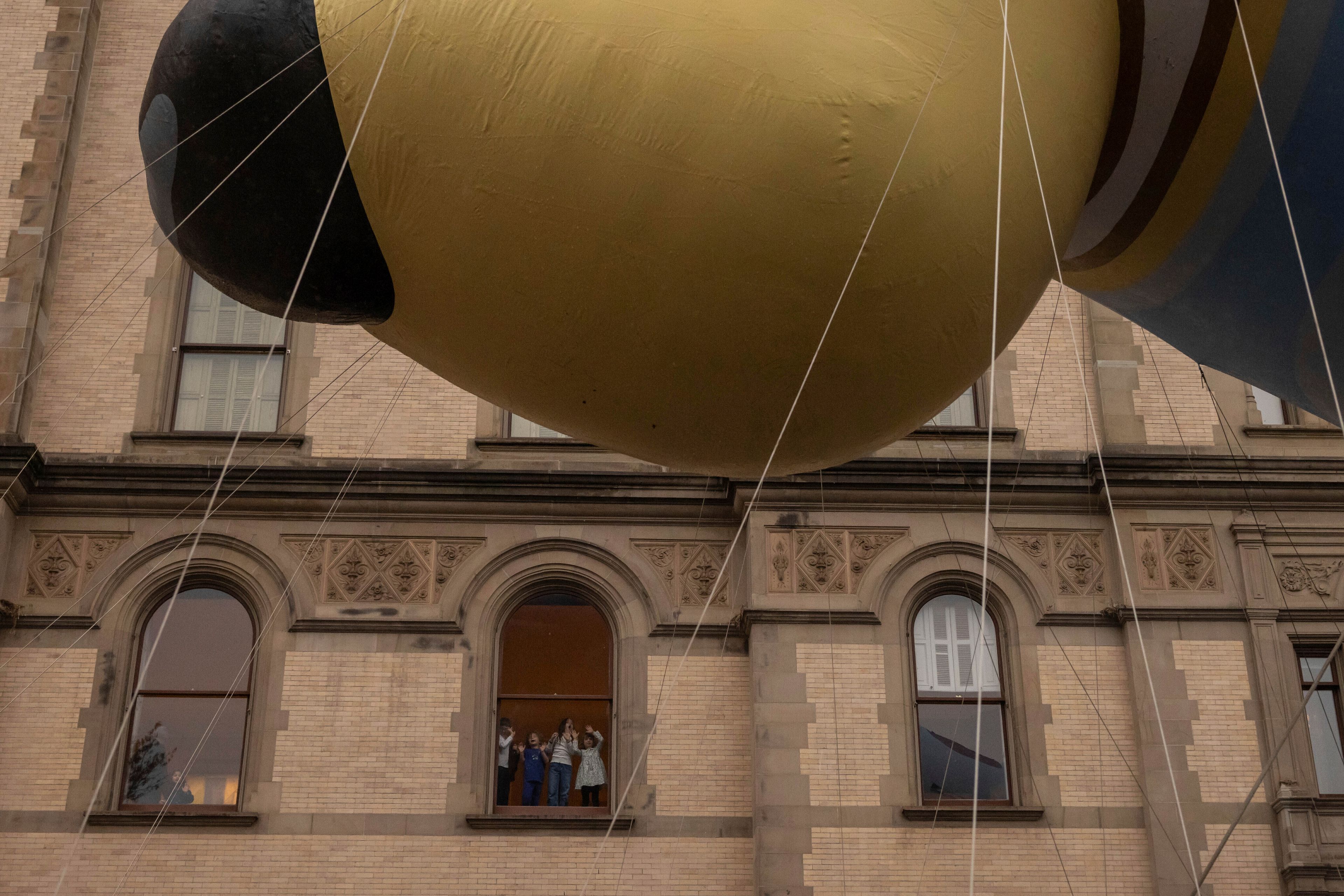 Spectators watch from a window as the balloon floats by along Central Park West during the Macy's Thanksgiving Day Parade, Thursday, Nov. 28, 2024, in New York. (AP Photo/Yuki Iwamura)