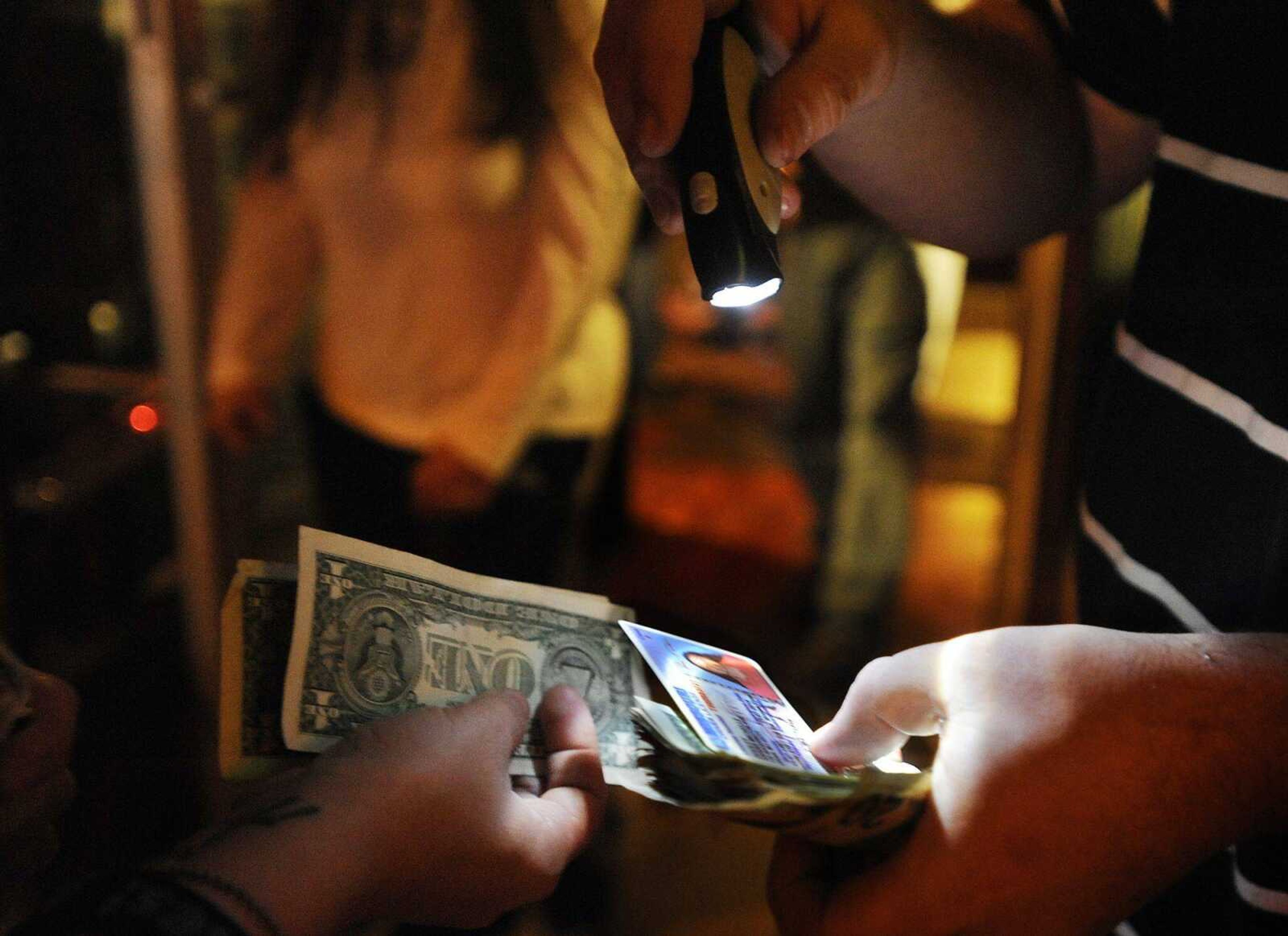 The doorman at the Rude Dog Pub, 123 N. Main St., checks a customer&#8217;s identification and collects a cover charge Saturday. (ADAM VOGLER)