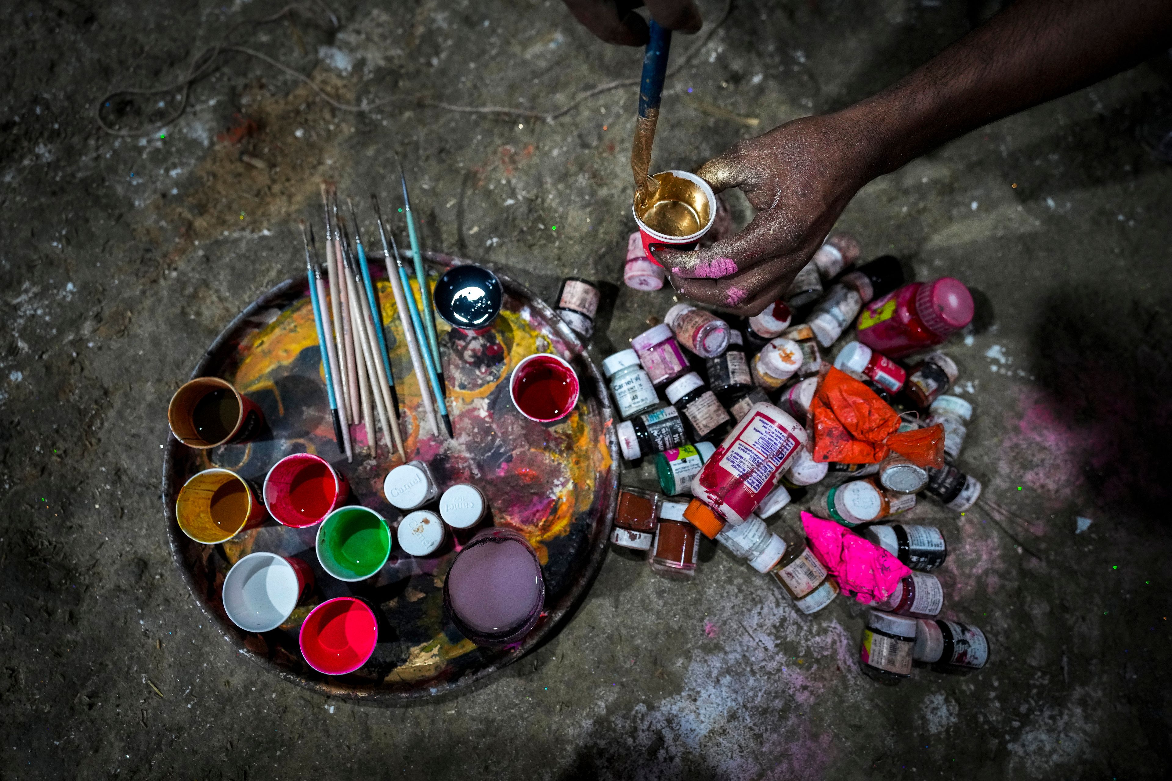 An artisan prepares colors to paint on a mud idol of the Hindu goddess Durga at a workshop during the Durga Puja festival in Guwahati, India, Saturday, Oct. 5, 2024. (AP Photo/Anupam Nath)