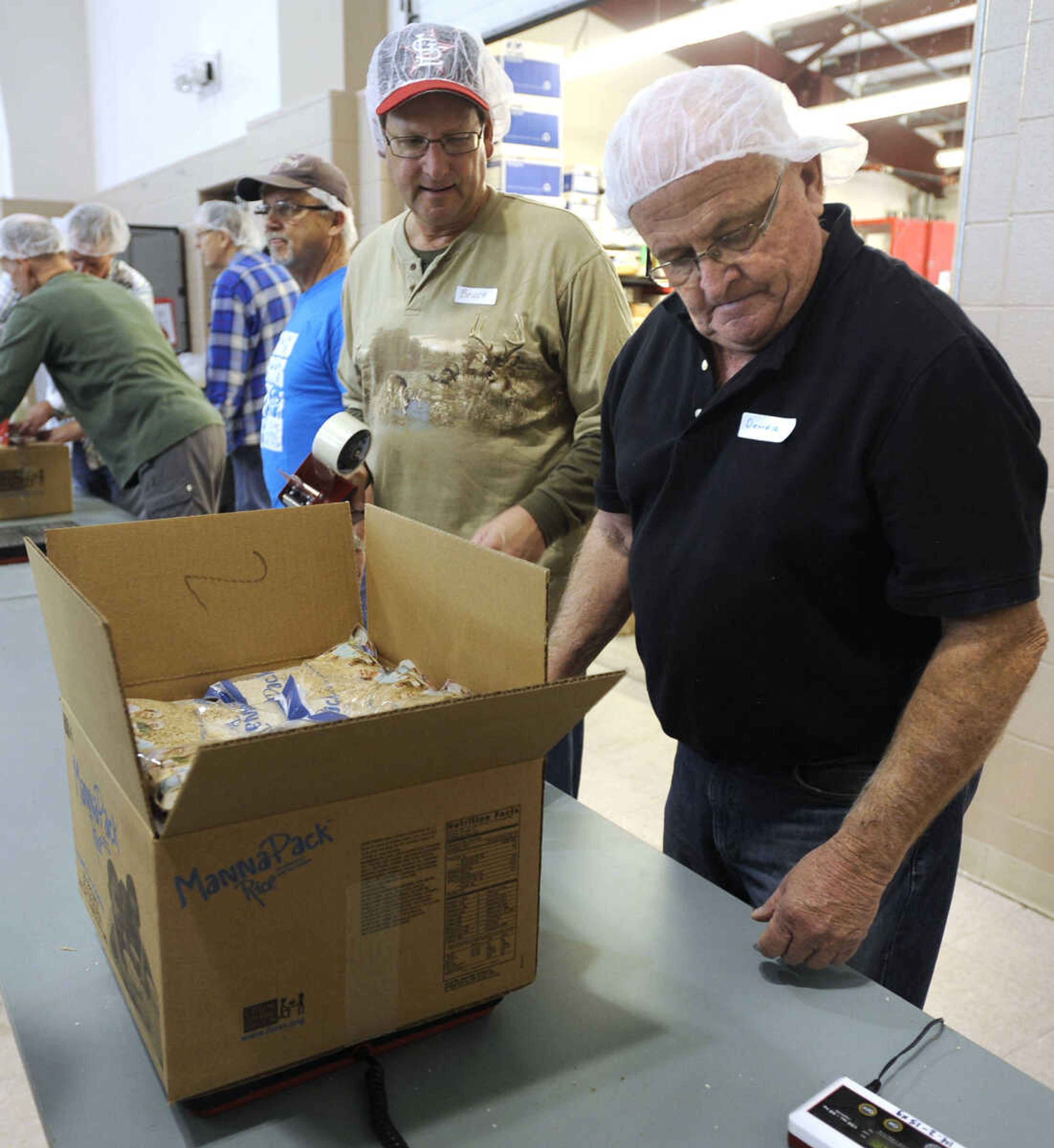 Dennis Roth, right, checks the weight of a box of MannaPack rice bags before sealing by Bruce Scherer at the Feed My Starving Children MobilePack event Sunday, Dec. 7, 2014 at the Osage Centre in Cape Girardeau.