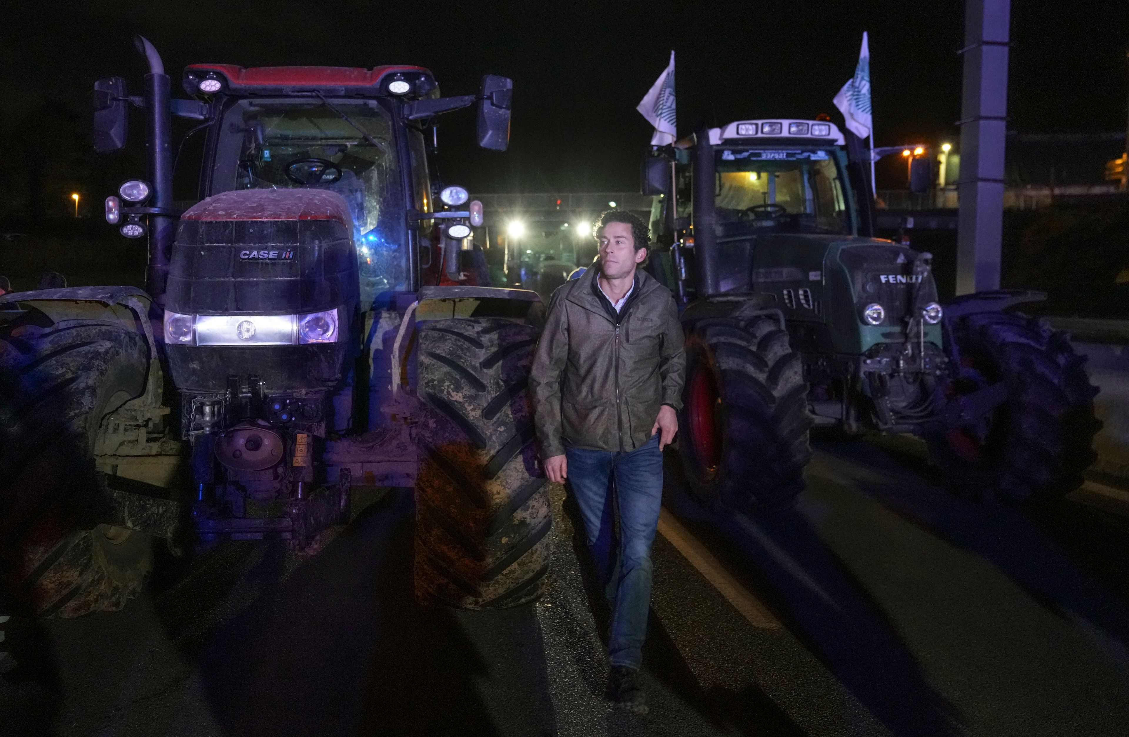 A farmers walks between tractors on a blocked highway in Velizy-Villacoublay, outside Paris, Sunday, Nov. 17, 2024. (AP Photo/Michel Euler)