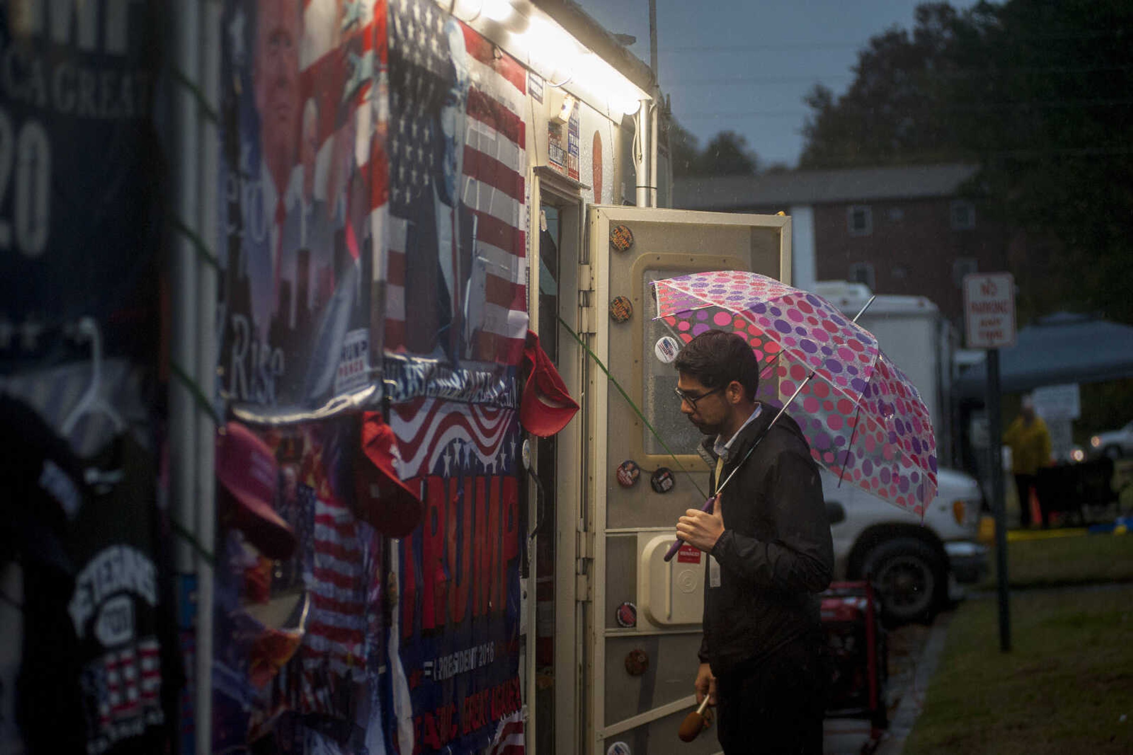 A reporter waits outside a merchandise van as dusk settles before President Trump's Make America Great Again rally at the Show Me Center Monday.