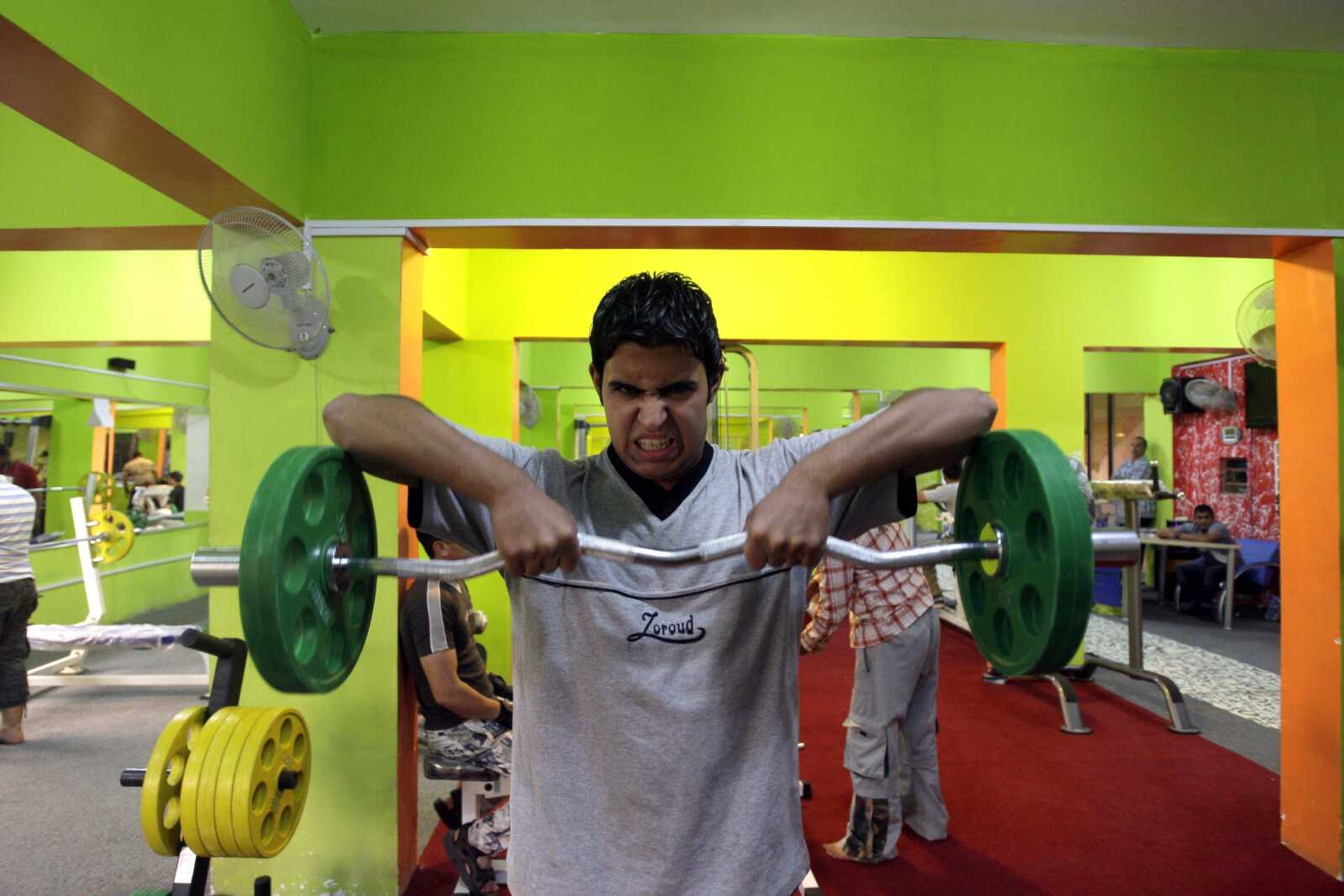 A man lifts weights at a gym May 10 in central Baghdad.  At least 300 gyms and fitness centers are believed to be operating in Baghdad, compared with about 30 before the 2003 U.S.-led invasion, according to people who work in the industry. (KHALID MOHAMMED ~ Associated Press)