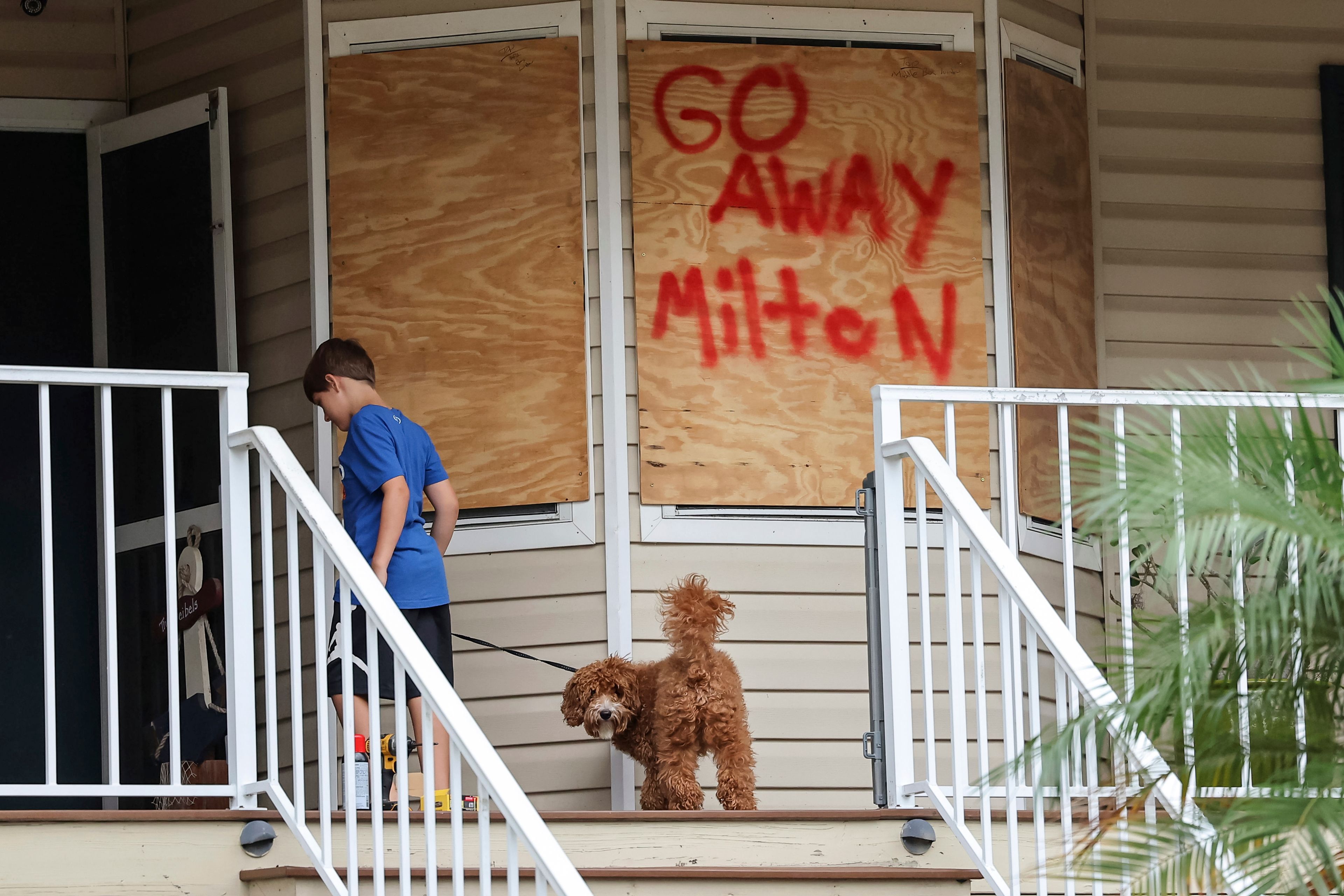 Noah Weibel and his dog Cookie climb the steps to their home as their family prepares for Hurricane Milton on Monday, Oct. 7, 2024, in Port Richey, Fla. (AP Photo/Mike Carlson)