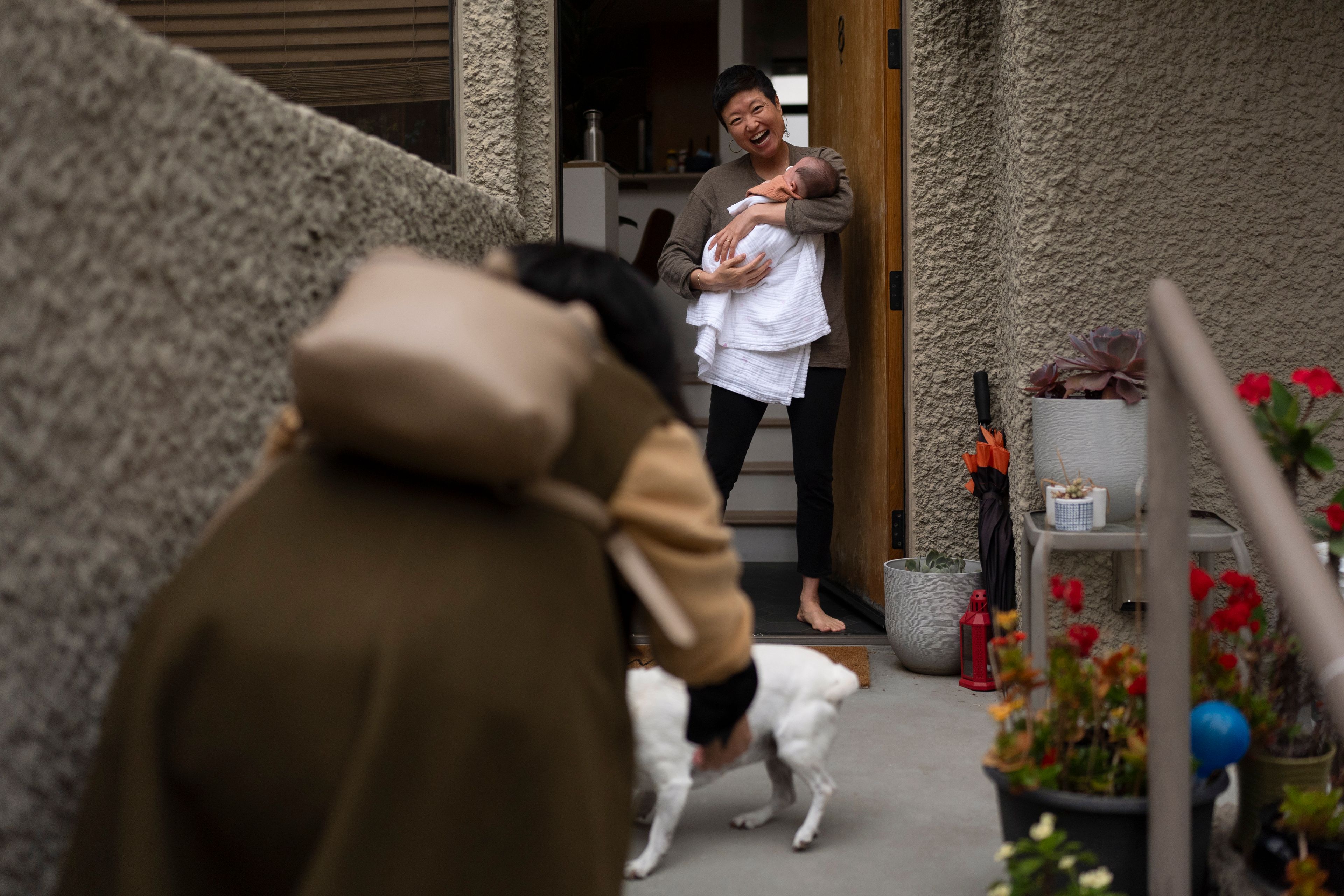 Robyn Joy Park, holds her newborn daughter, Rae, at her home in Pasadena, Calif., as she greets her friend, Michaela Dietz, Friday, April 19, 2024. Both women are adoptees from South Korea, and both learned the identities listed on their adoption paperwork actually belonged to other children. (AP Photo/Jae C. Hong)