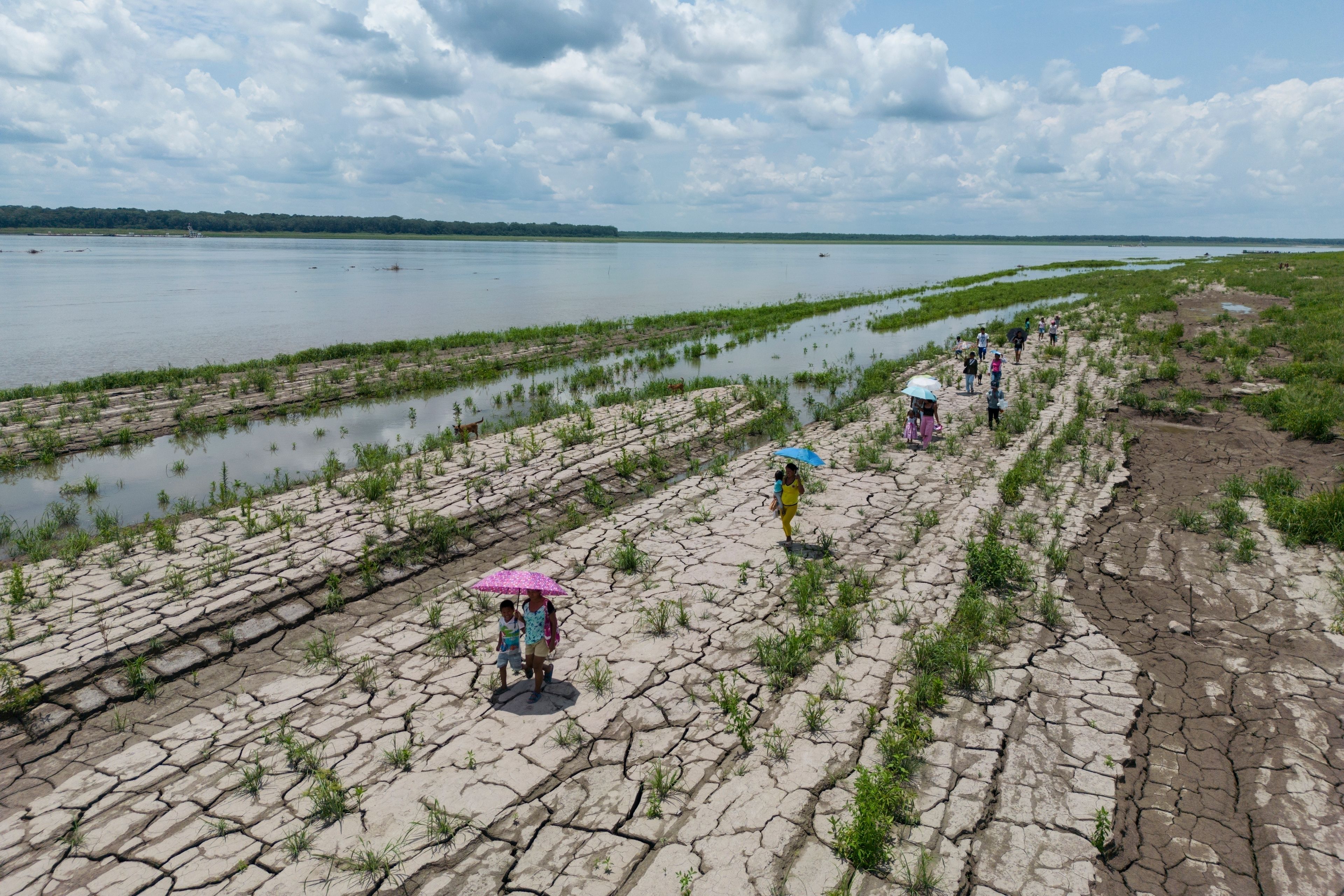 FILE - People walk through a part of the Amazon River that shows signs of drought in Santa Sofia, on the outskirts of Leticia, Colombia, Oct. 20, 2024. (AP Photo/Ivan Valencia, File)