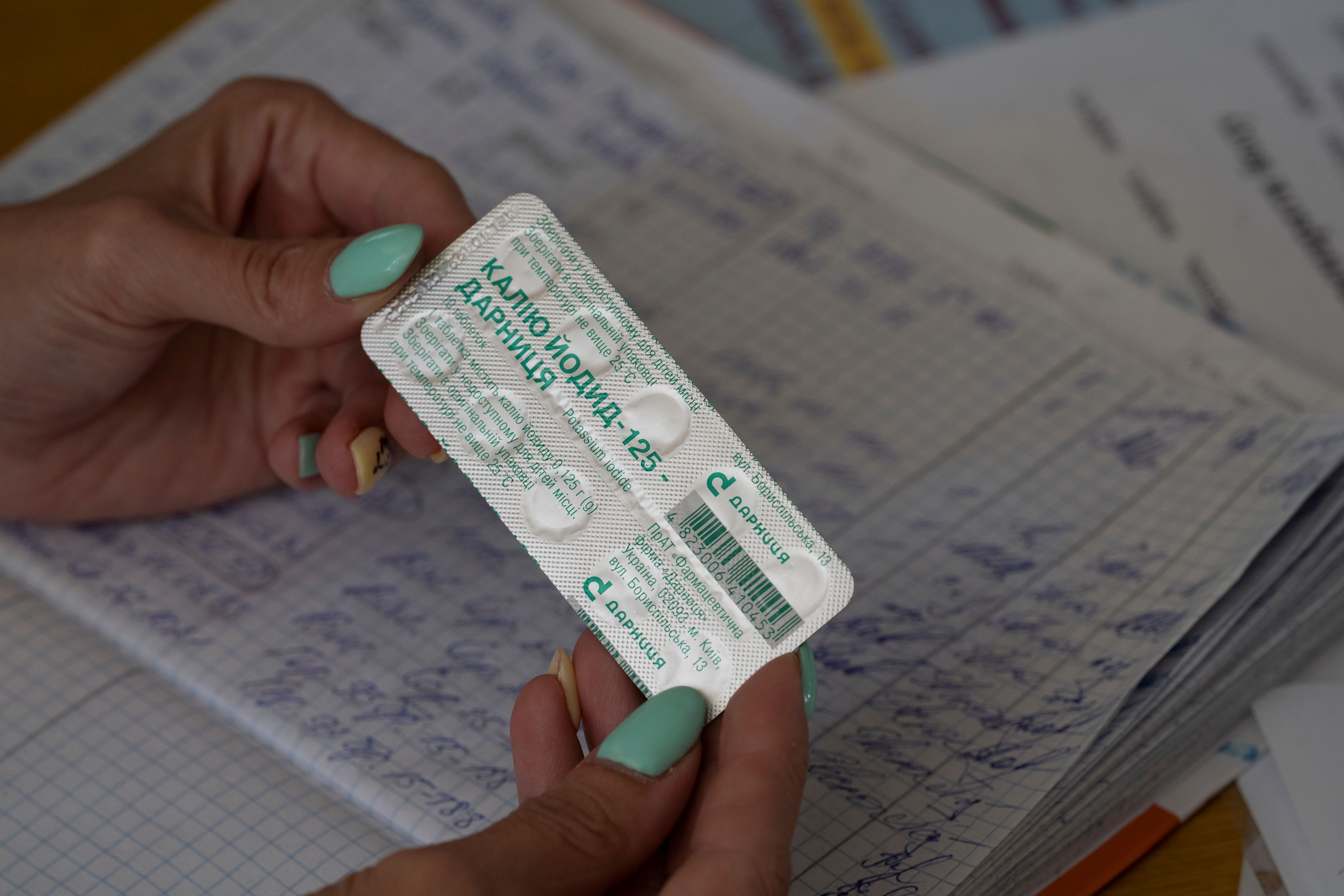 FILE - In this Sept. 2, 2022, photo, a woman distributes packs of iodine tablets to residents at a local school in case of a radiation leak in Zaporizhzhia, Ukraine. The war in Ukraine heightened fears about fallout in the city, which is near a Russian-controlled nuclear power plant. (AP Photo/Leo Correa, File)