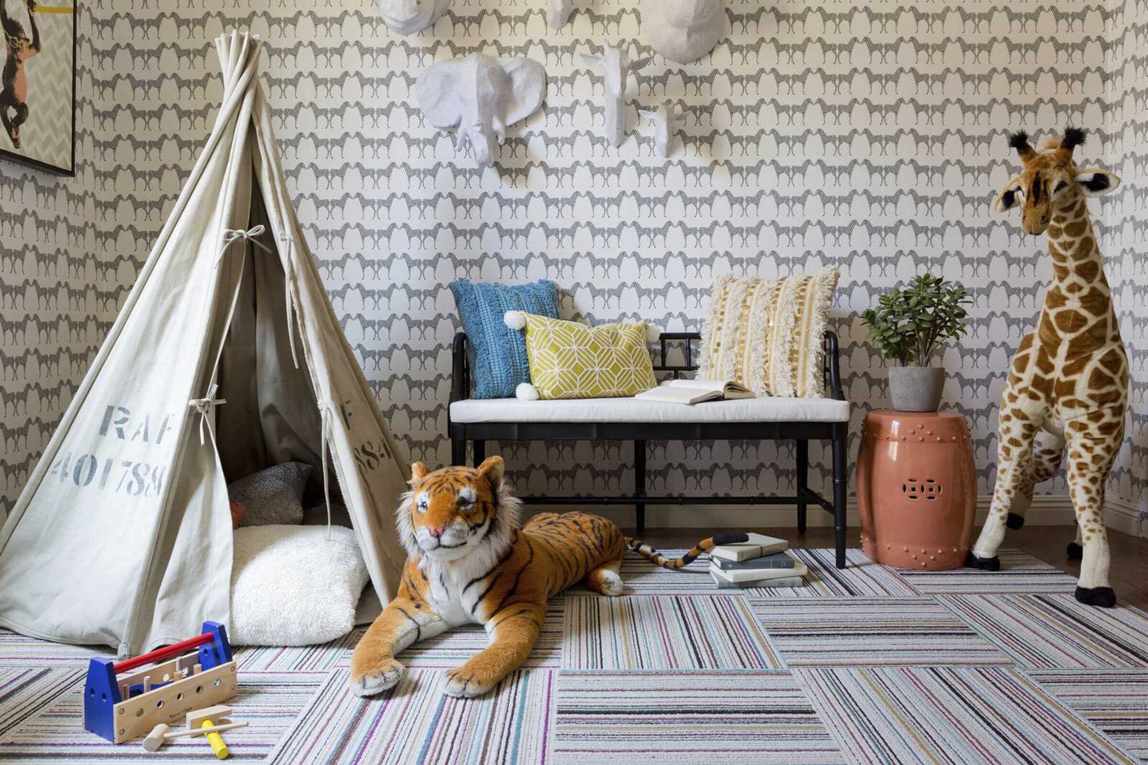 This undated photo provided by Hermosa Beach, Calif., based designer Kate Lester shows a safari-themed playroom designed by Lester near Los Angeles. A soothing palette and unexpected artsy elements like the animal head wall art and Marley + Malek Kids wallpaper assure the space will grow with the kids. Lester says she and her team use removable floor tiles like these on almost all their projects. They're rugged and washable, and if one gets stained it can be changed out. (Amy Bartlam/Kate Lester via AP)