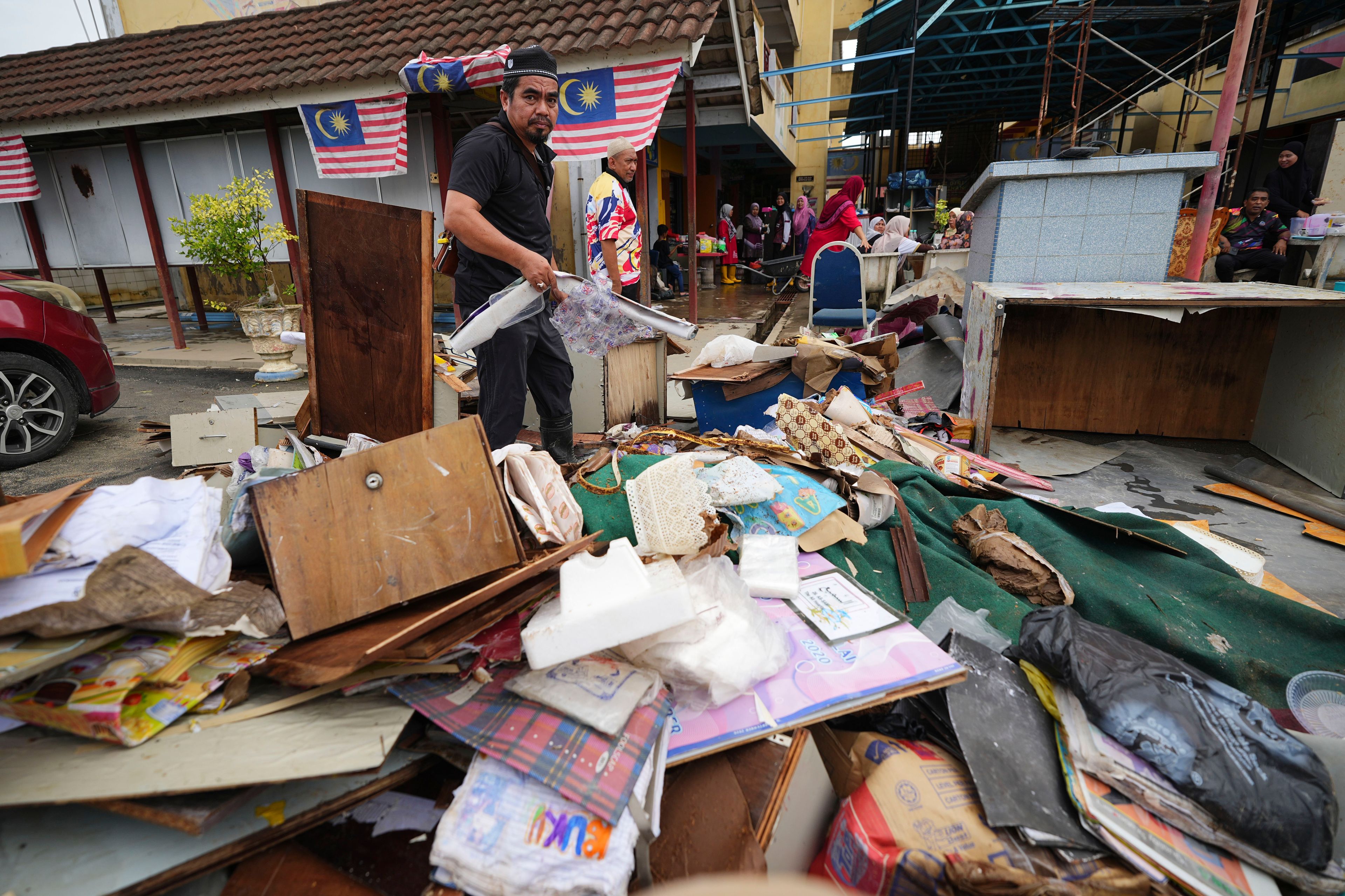 A man sorts items removed from a school affected by a flood in Tumpat, on the outskirts of Kota Bahru, Malaysia, Tuesday, Dec. 3, 2024. (AP Photo/Vincent Thian)