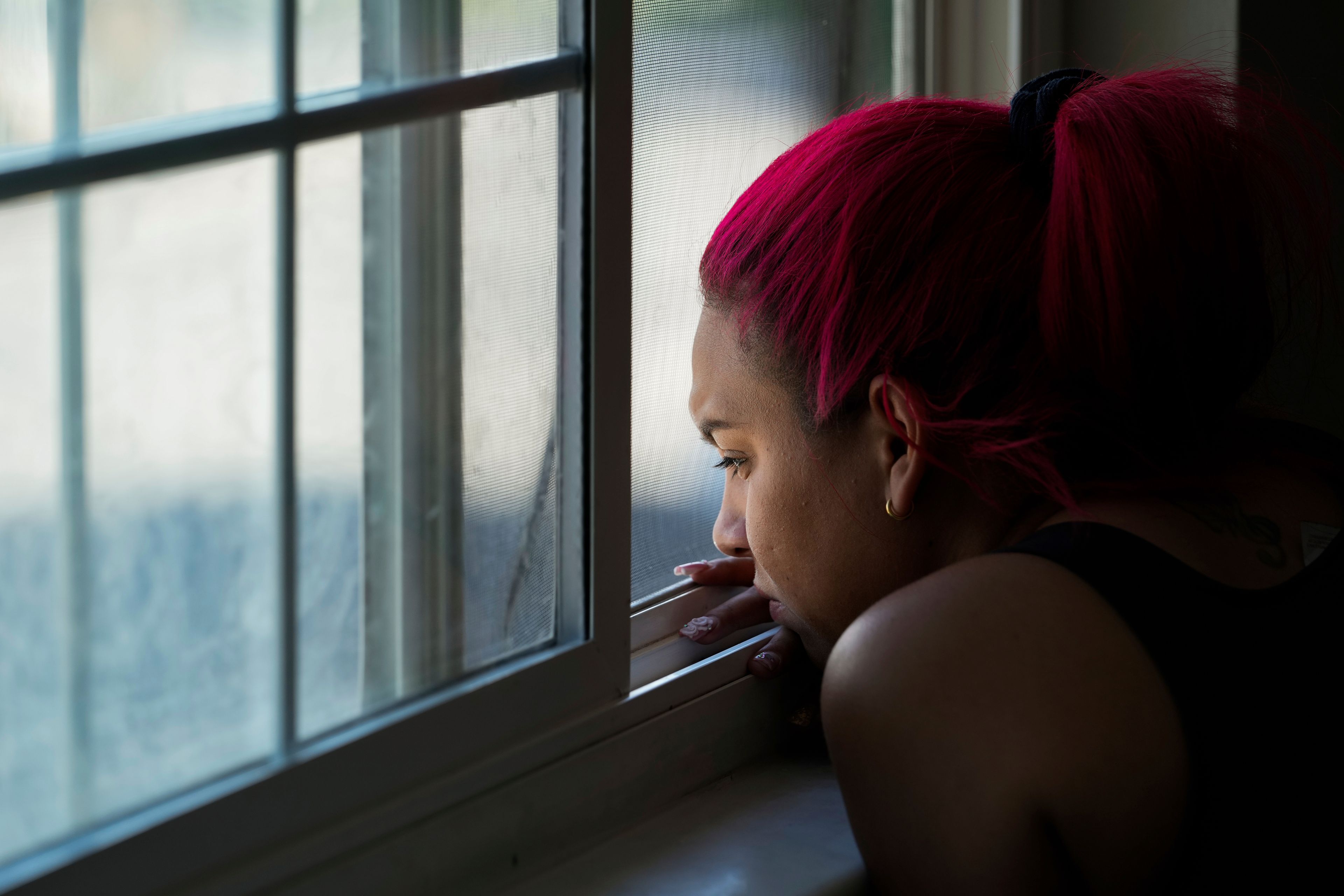 Gabriela Ramírez watches from a window as two of her friends try to repair her car Thursday, Aug. 29, 2024, in Aurora, Colo. (AP Photo/Godofredo A. Vásquez)