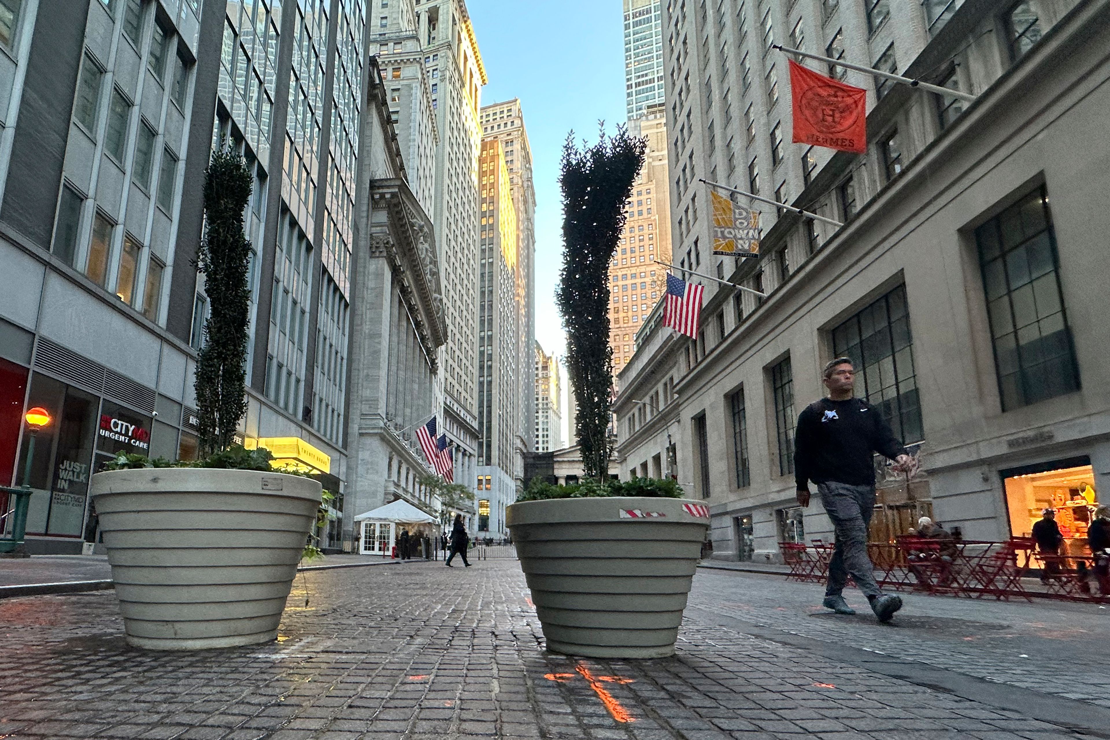 FILE - People pass the New York Stock Exchange, at rear, in New York's Financial District on Oct. 16, 2024. (AP Photo/Peter Morgan, File)