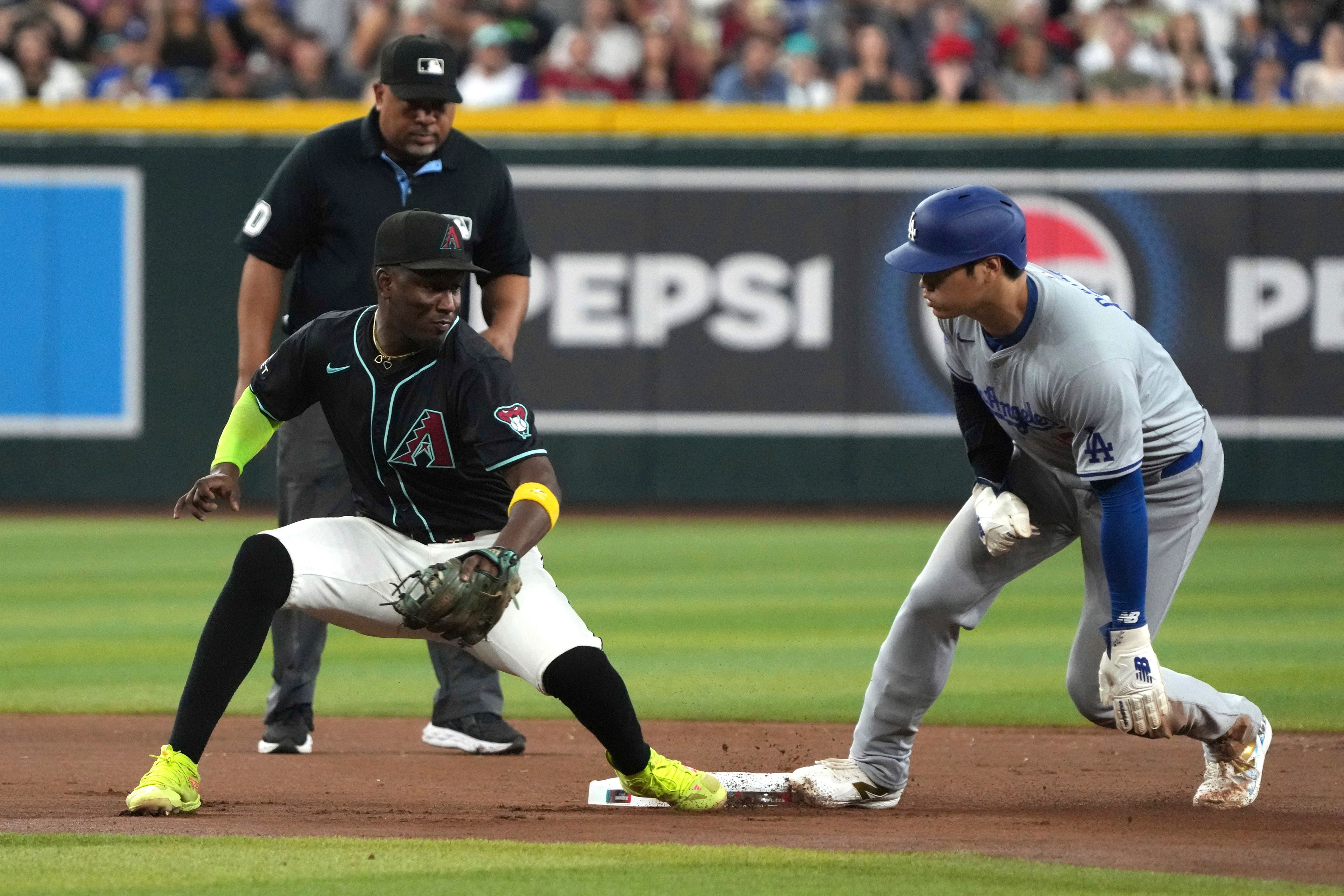 Los Angeles Dodgers' Shohei Ohtani, right, steals second base in front of Arizona Diamondbacks shortstop Geraldo Perdomo, front left, in the seventh inning during a baseball game, Monday, Sept. 2, 2024, in Phoenix. (AP Photo/Rick Scuteri)