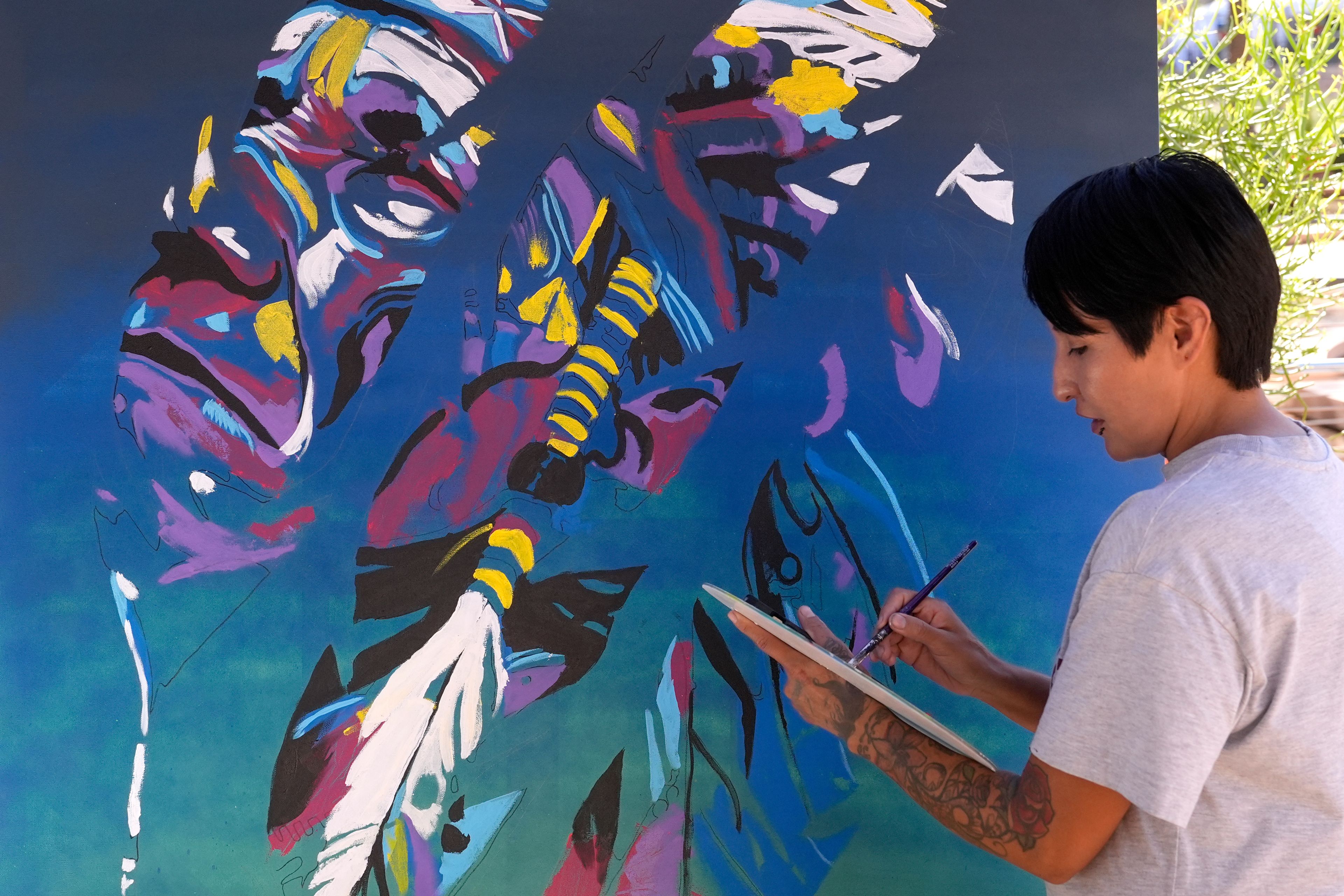 Artist Richelle Key works on the painting "Democracy Is Indigenous" during an Indigenous Peoples' Day event Monday, Oct. 14, 2024, in Phoenix. (AP Photo/Ross D. Franklin)