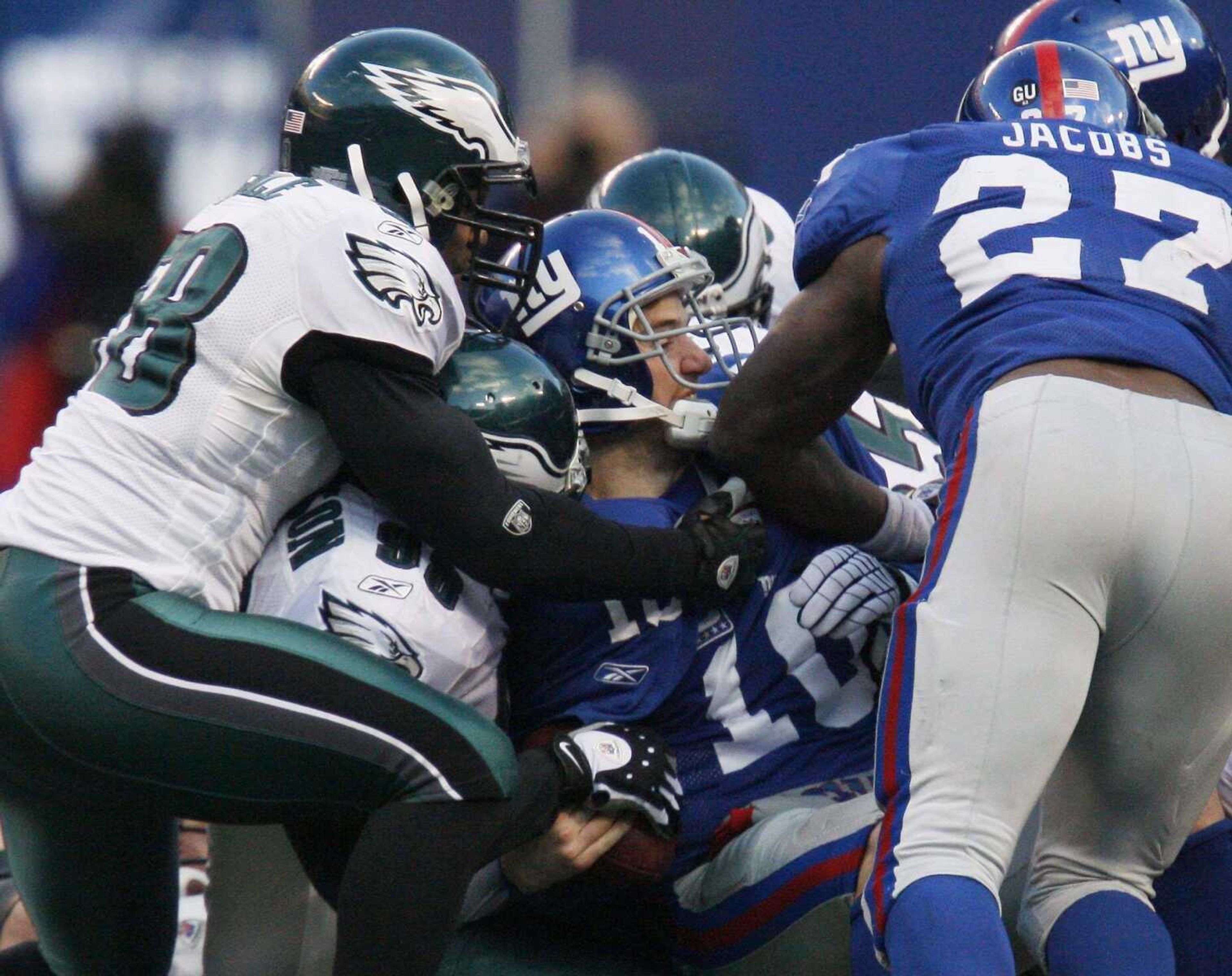 New York Giants quarterback Eli Manning is stopped on a fourth-down run by the Eagles' Trent Cole (58) and Mike Patterson (98).