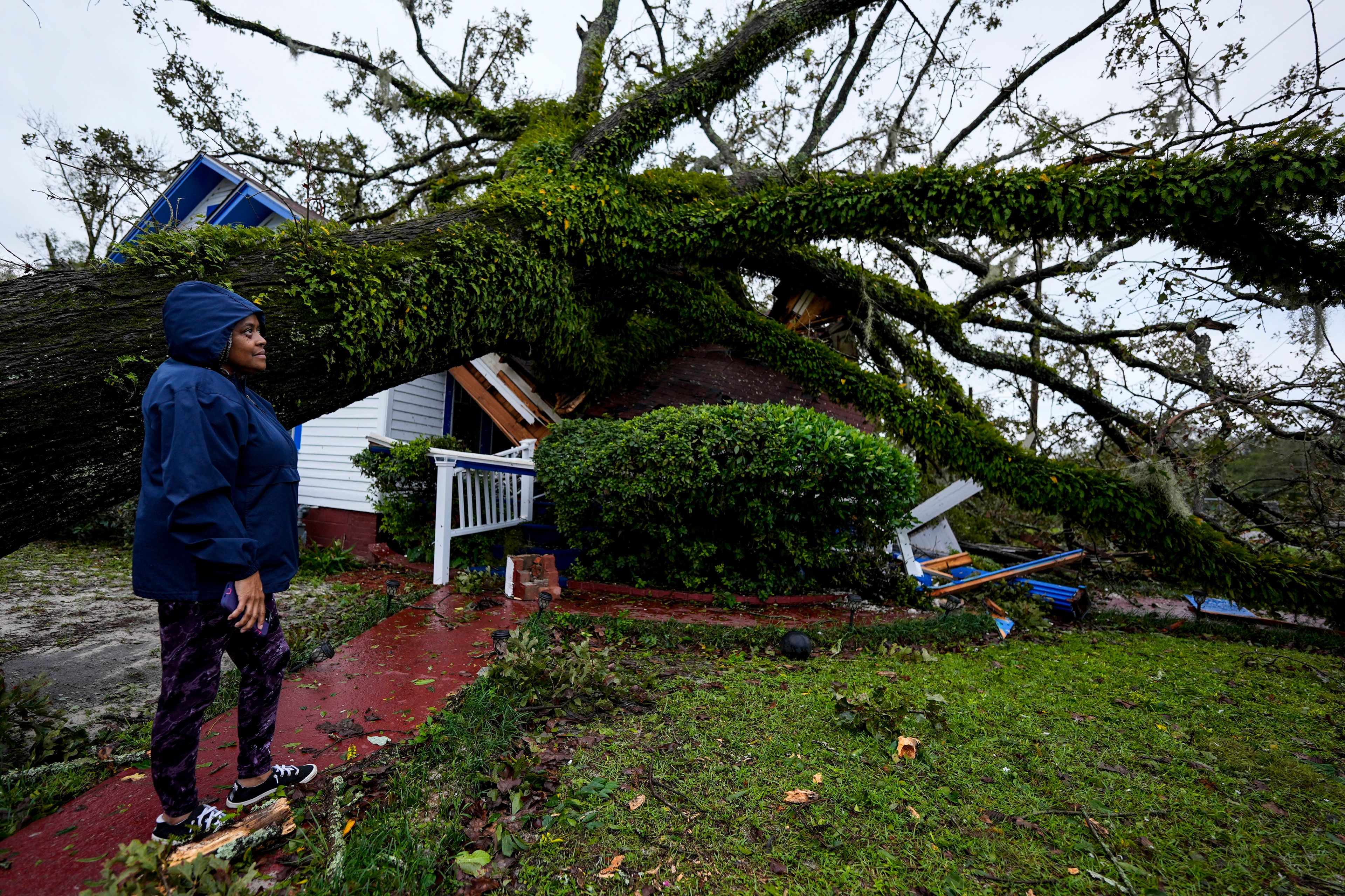 Rhonda Bell looks on after an Oak tree landed on her 100-year-old home after Hurricane Helene moved through, Friday, Sept. 27, 2024, in Valdosta, Ga. (AP Photo/Mike Stewart)