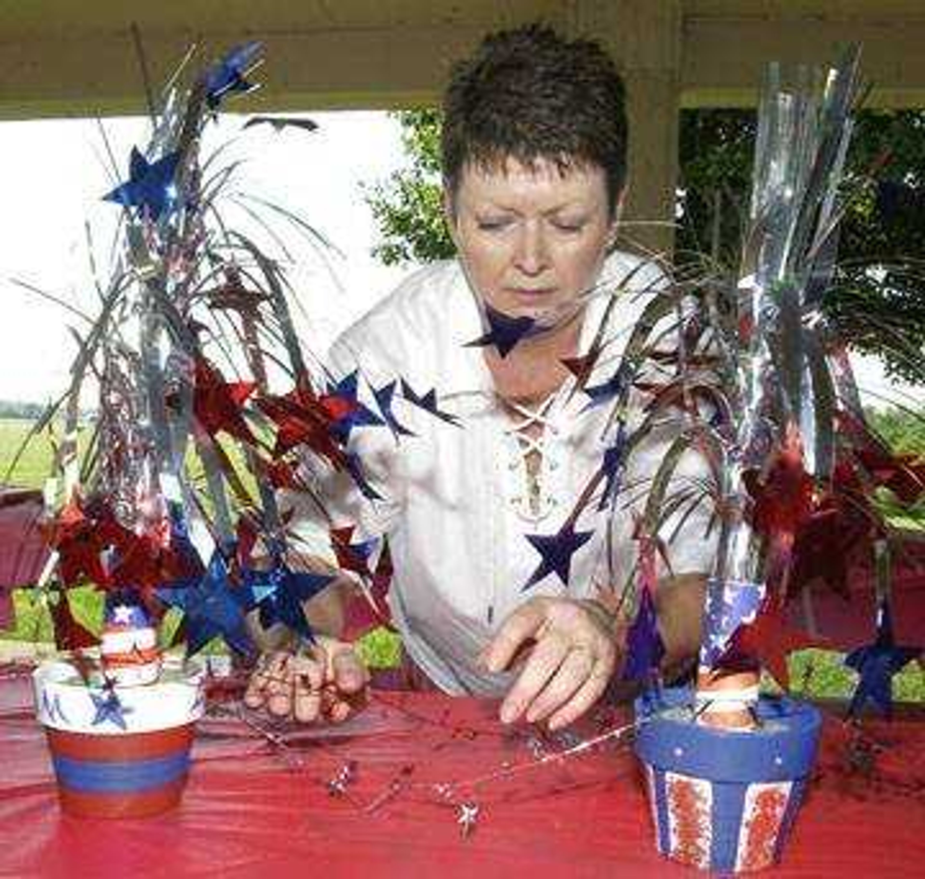 Elaine Martin positioned table decorations for a wedding rehearsal dinner Friday, July 4, 2003 at Cape Girardeau County Park North.