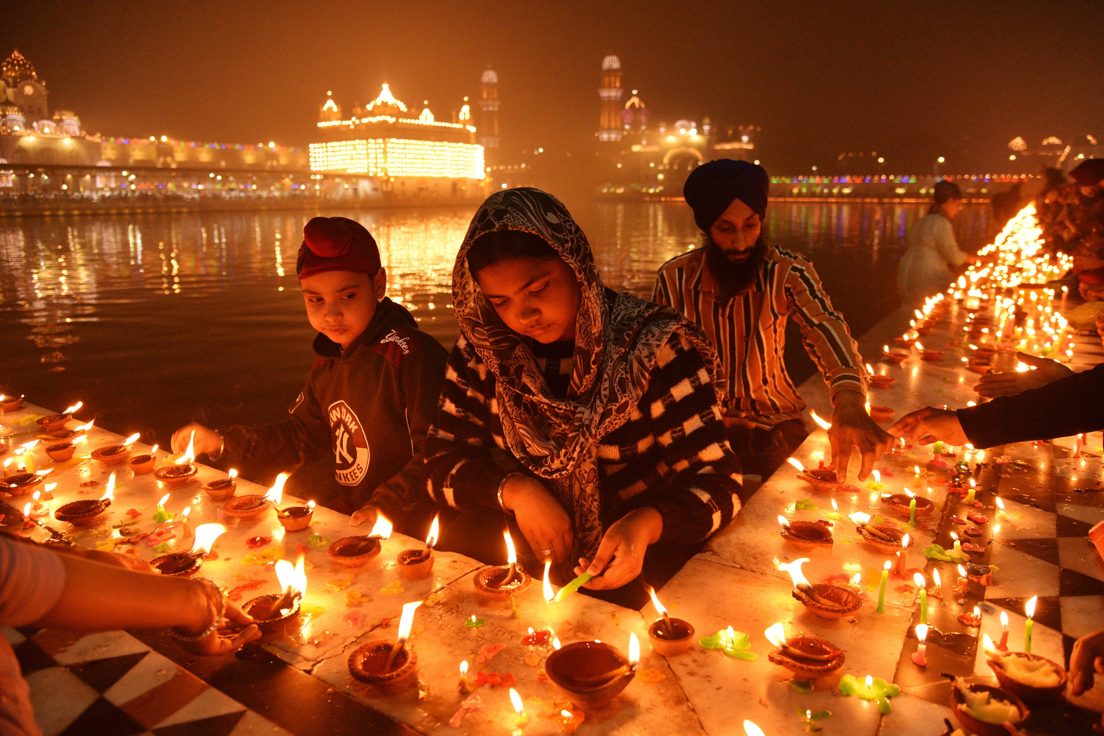 Sikh devotees light clay lamps next to the pond surrounding the Golden Temple as they celebrate the birth anniversary of the first Sikh guru, Guru Nanak, in Amritsar, India, Friday, Nov. 15, 2024. (AP Photo/Prabhjot Gill)