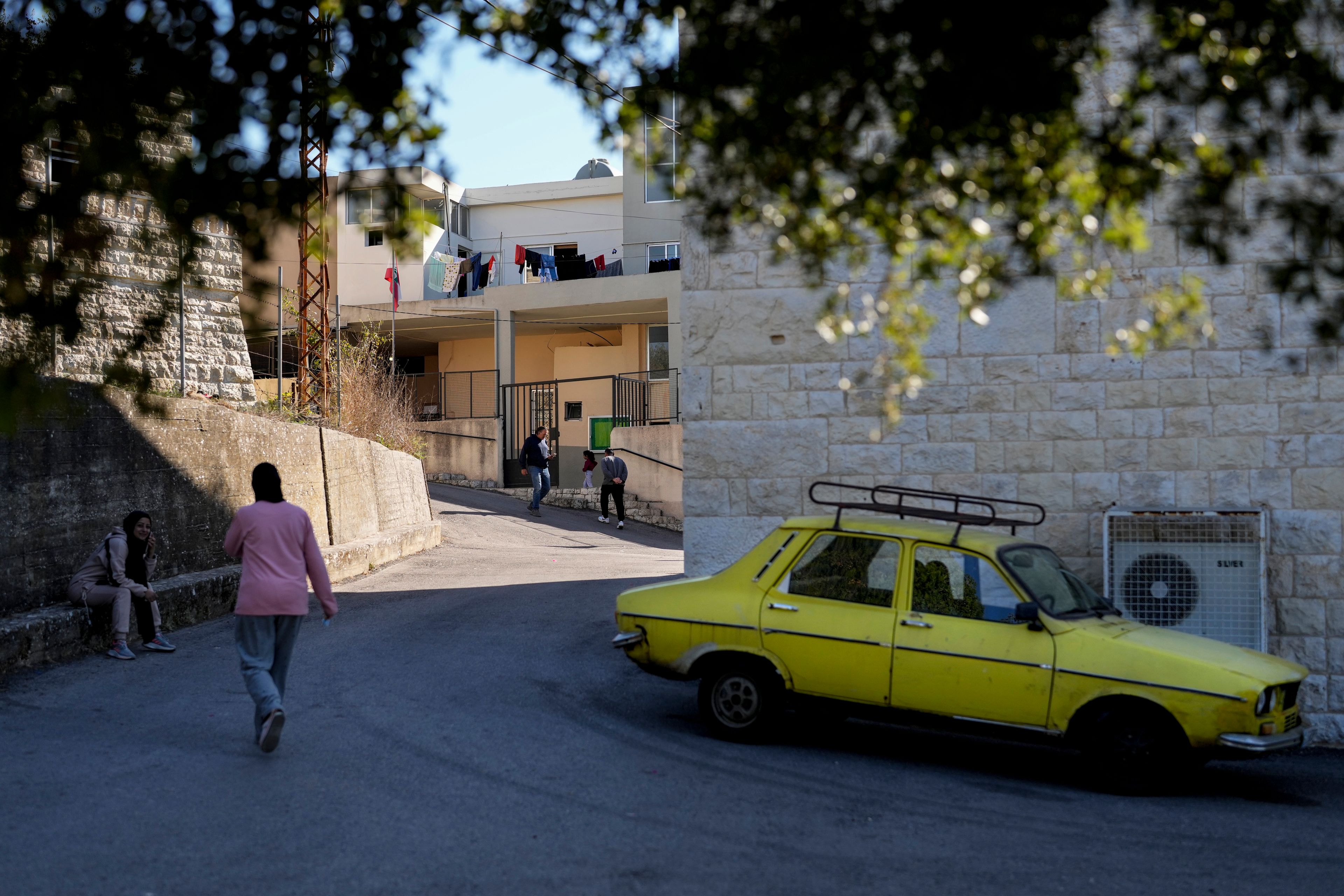 Displaced people who fled southern Lebanon with their families during the ongoing Hezbollah-Israel war walk outside a school in the village of Ebrine, northern Lebanon, Thursday, Oct. 24, 2024. (AP Photo/Hassan Ammar)