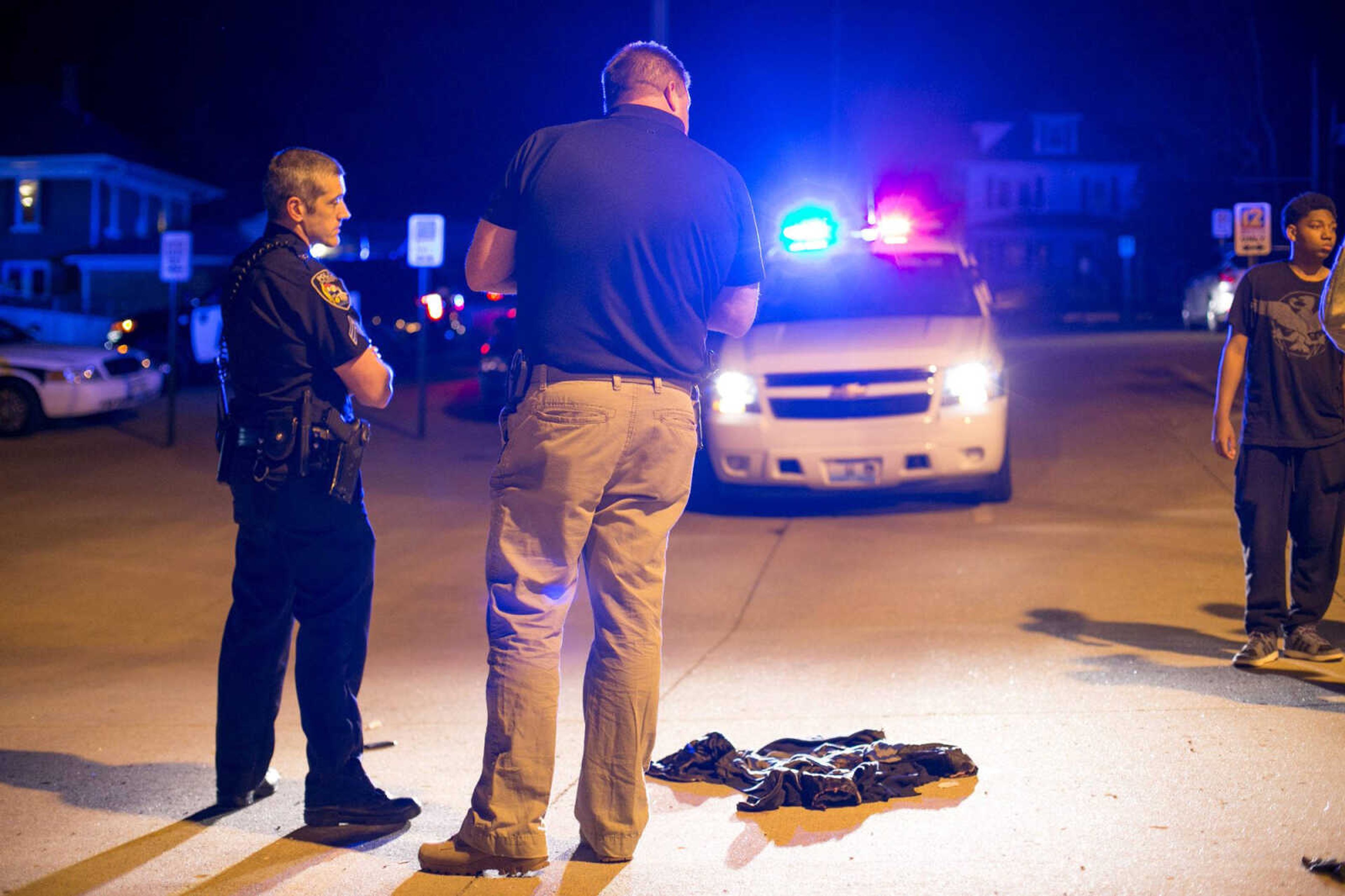 Police officers watch over the victim’s clothes after a shooting Thursday in the KFVS12 parking lot in downtown Cape Girardeau.