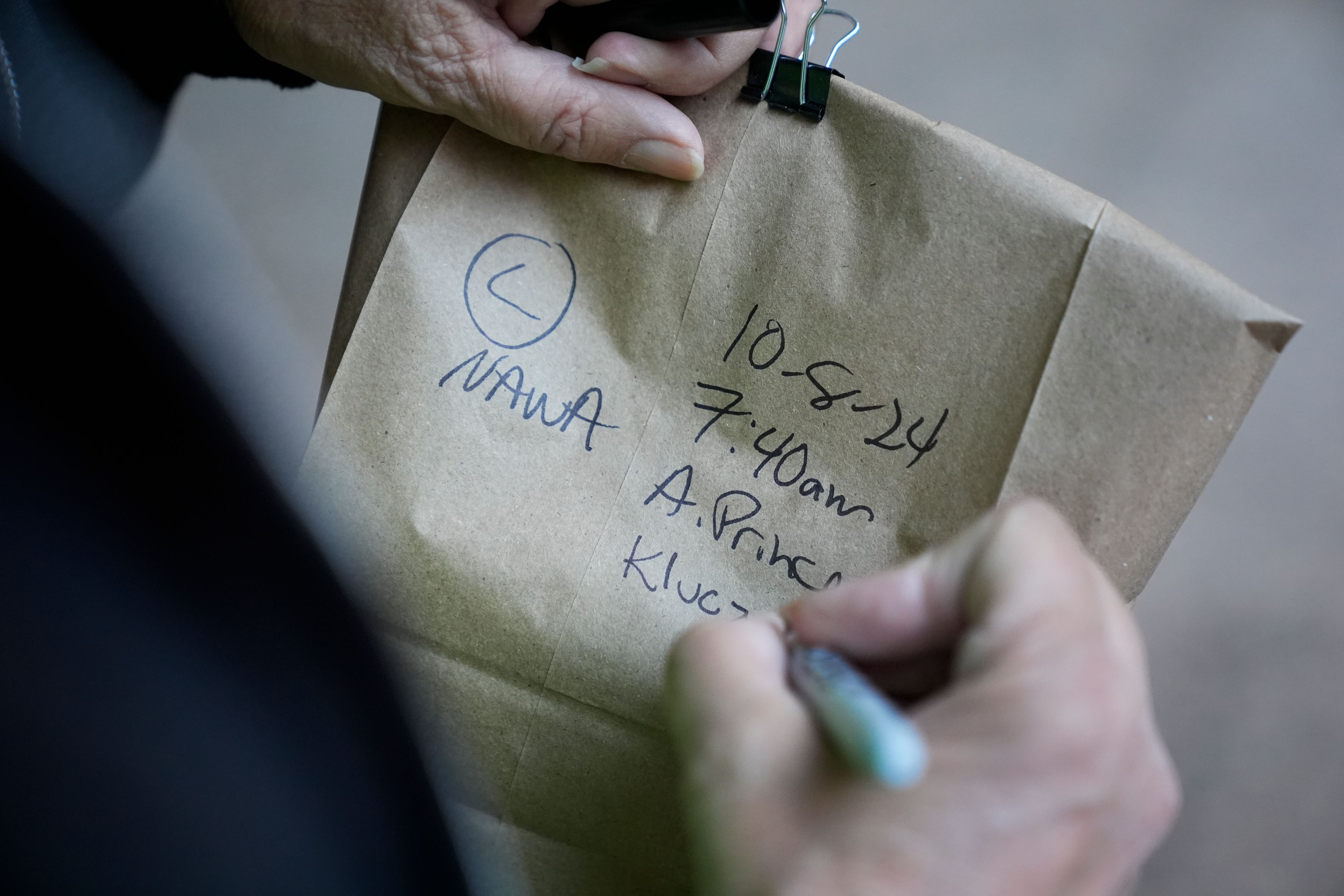 Chicago Bird Collision Monitors Director Annette Prince writes details on a paper bag containing an injured Nashville warbler that likely struck a glass window pane Tuesday, Oct. 8, 2024, in downtown Chicago. (AP Photo/Erin Hooley)