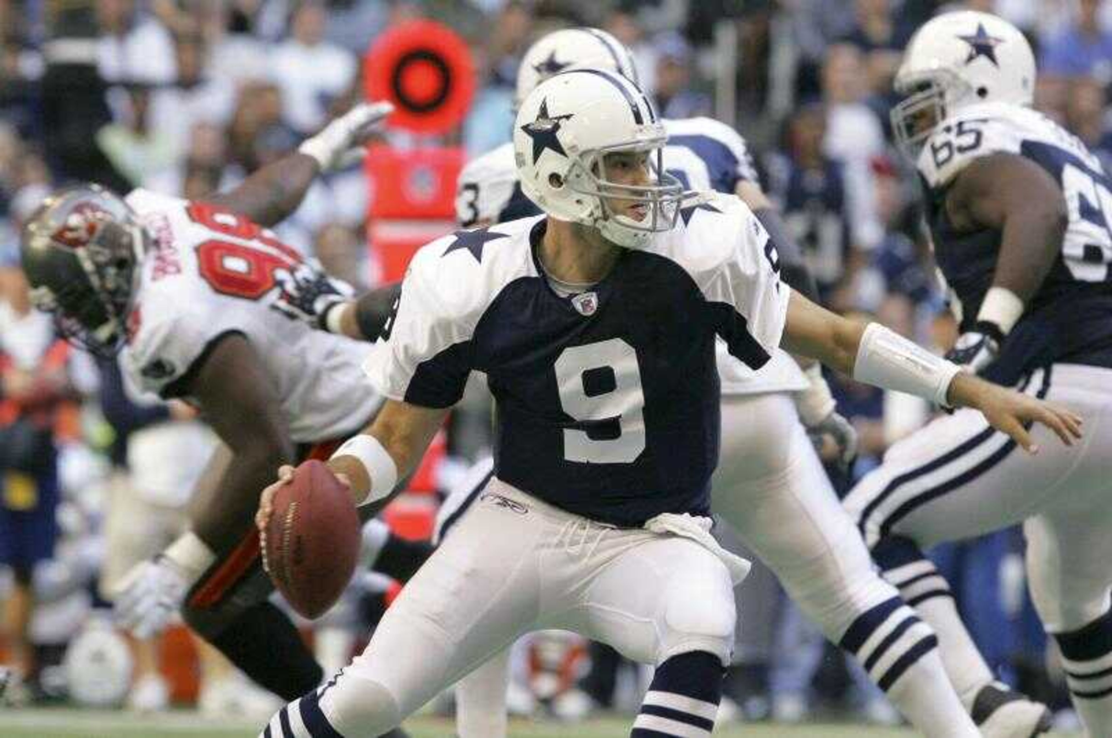 Dallas Cowboys quarterback Tony Romo scrambled while looking for an open receiver during Thursday's game against Tampa Bay. Romo passed for five touchdowns, tying a team record and becoming the first Cowboys quarterback to accomplish the feat on Thanksgiving. (L.M. OTERO ~ Associated Press)