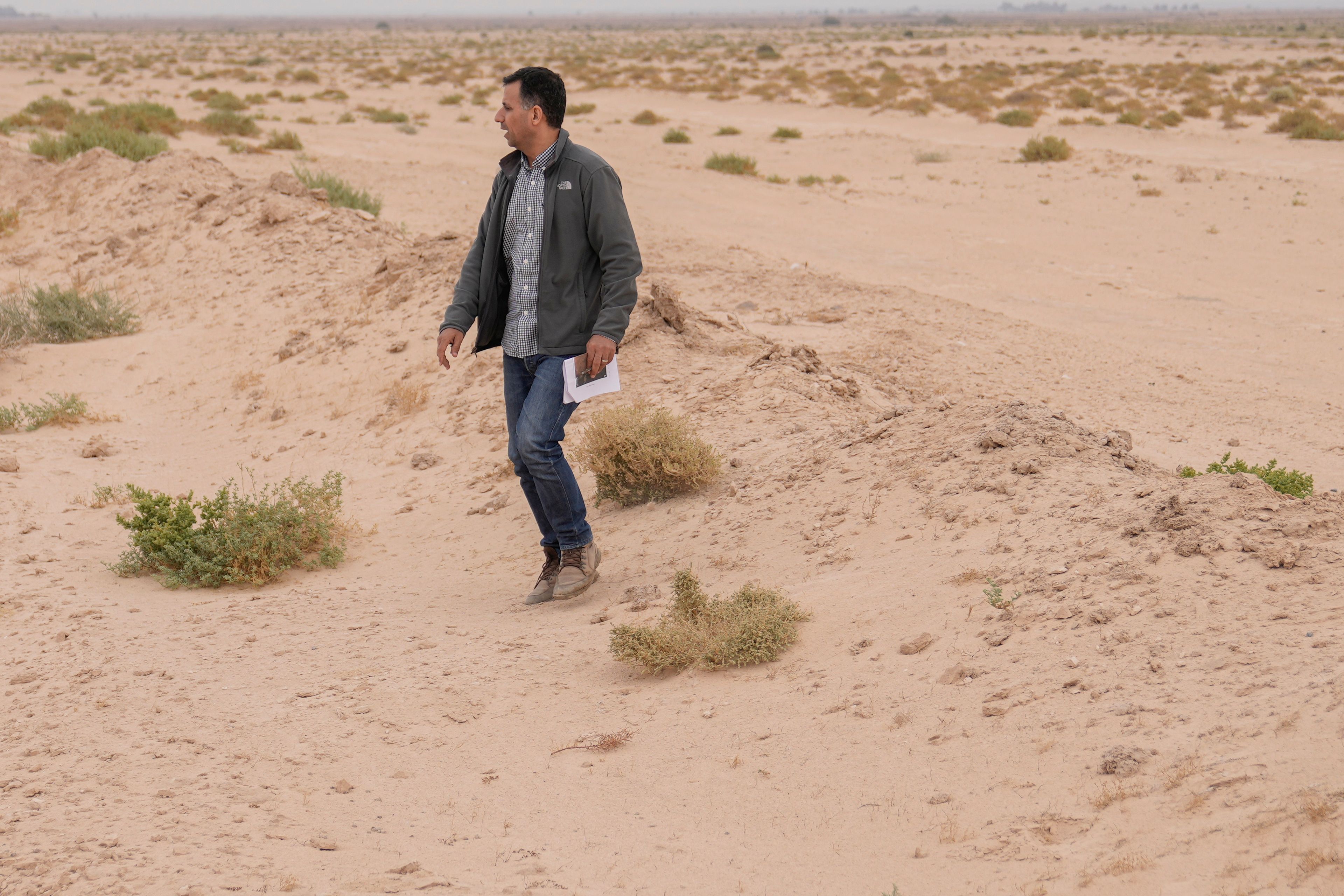 Dr Jaafar al Jotheri holds satellite images and explores the site of the Battle of al-Qadisiyah, which was fought in Mesopotamia - present-day Iraq - in the 630s AD between Arab Muslims and the army of the Sassanid Persian dynasty during a period of Muslim expansion. Abu Sakhir district- southern Najaf, Iraq, Sunday, Nov.10, 2024. (AP Photo/Hadi Mizban)