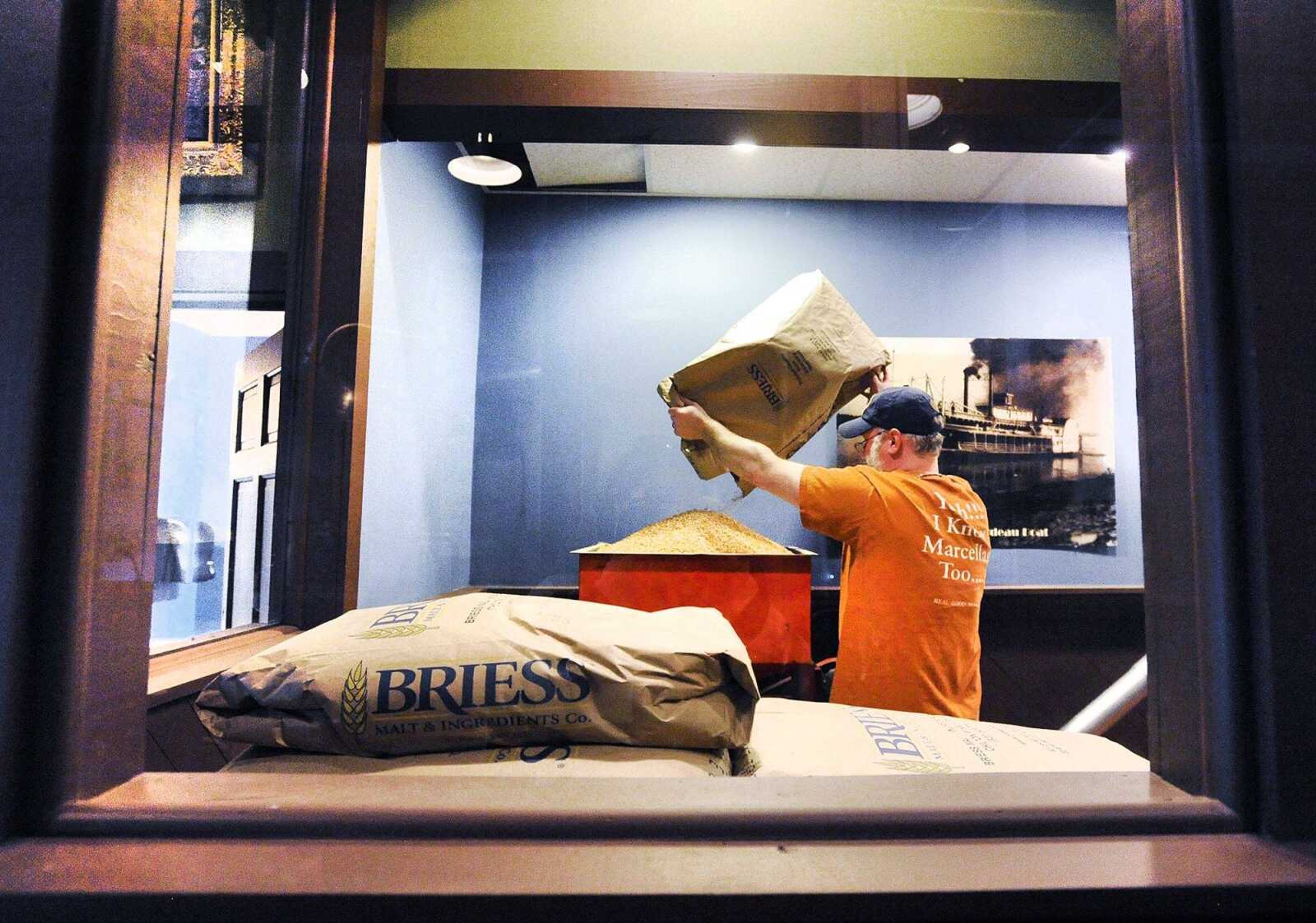 Mike Mills, brewmaster at Buckner's, adds dry ingredients to the mill to be transported through the auger to the mash bin for brewing Tuesday in downtown Cape Girardeau. Mills was brewing a batch of Bee's Sneeze Honey Wheat beer. (Laura Simon)