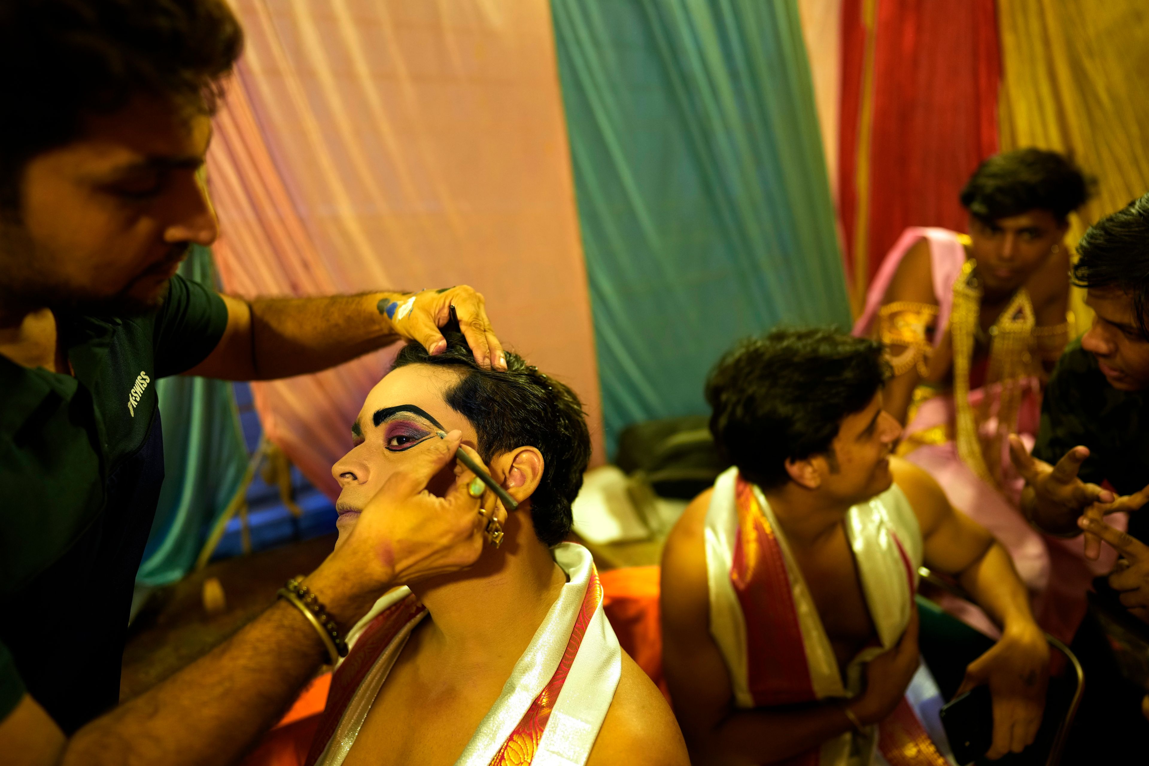 A makeup artist gets an actor ready backstage before the start of Ramleela, a dramatic folk re-enactment of the life of Hindu god Rama according to the ancient Hindu epic Ramayana, in New Delhi, India, Saturday, Oct. 5, 2024. (AP Photo/Manish Swarup)