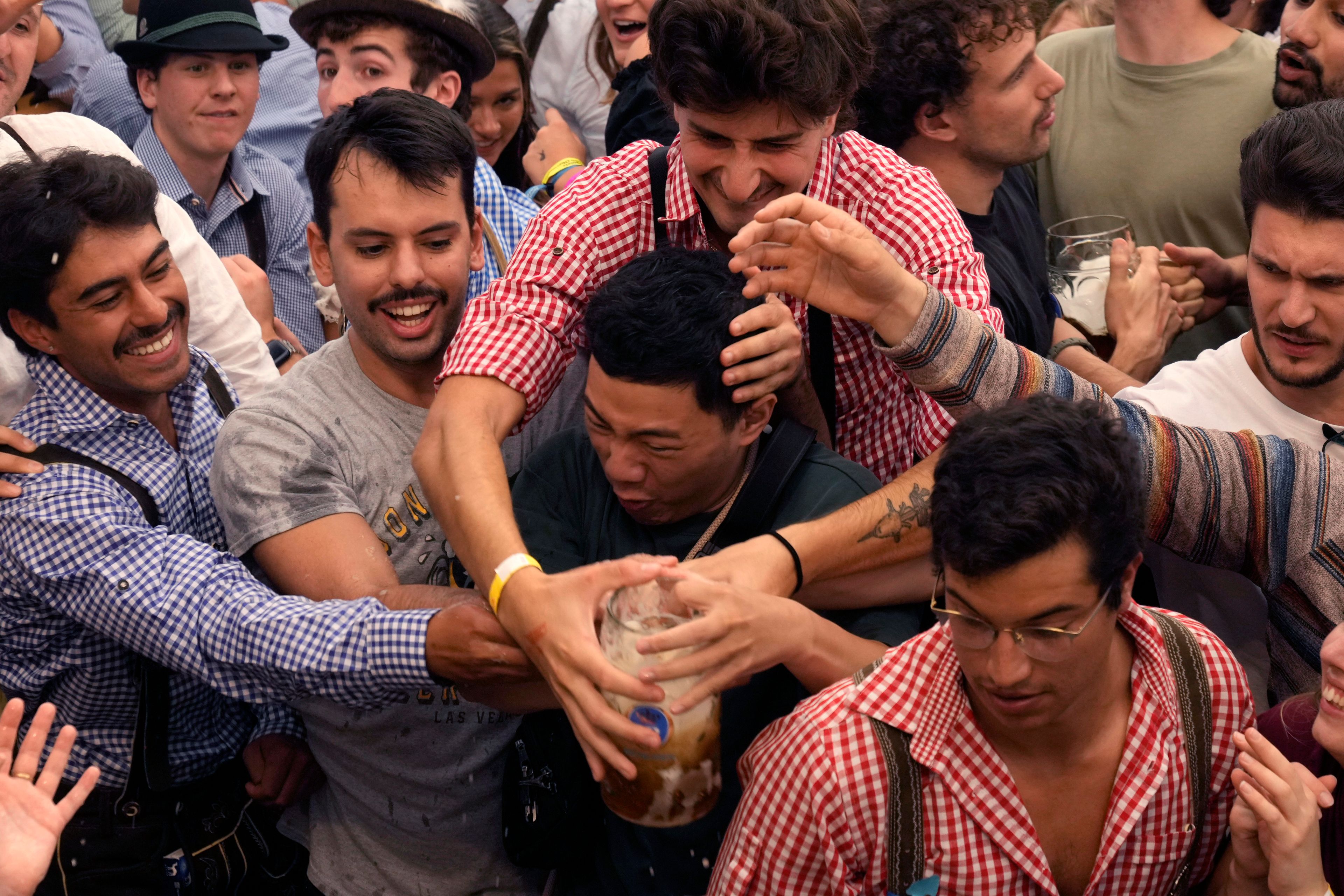 Festival goers fight for the first glasses of beer at the Hofbraehaus beer tent on day one of the 189th 'Oktoberfest' beer festival in Munich, Germany, Saturday, Sept. 21, 2024. (AP Photo/Matthias Schrader)