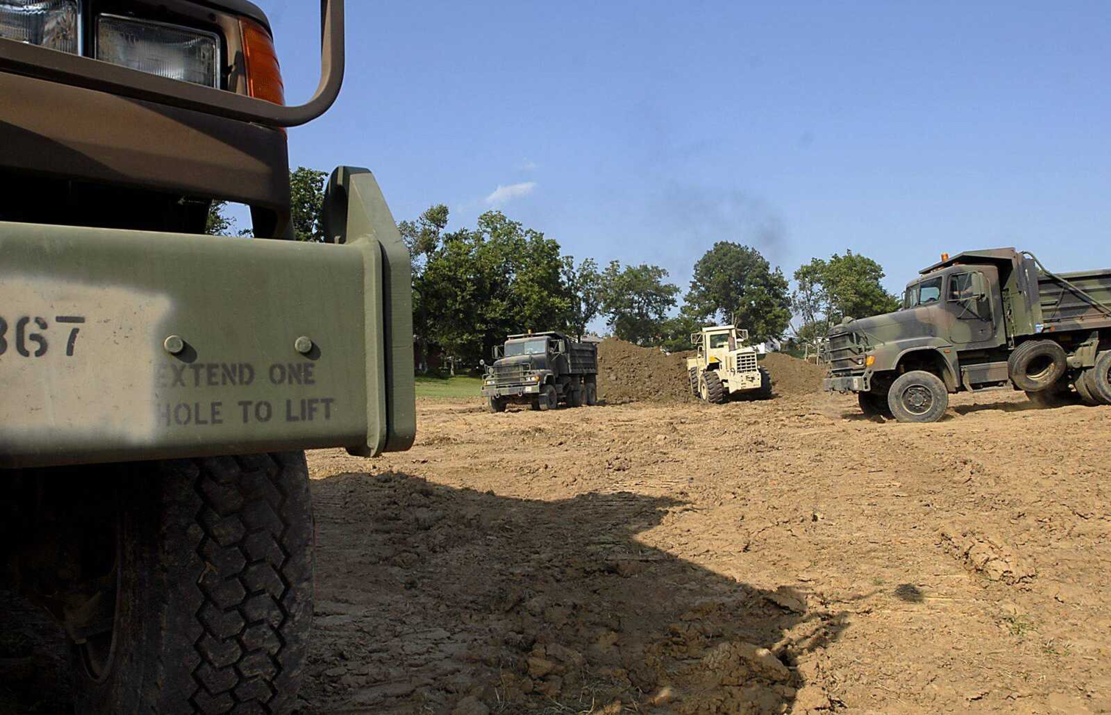 National Guard dump trucks wait Friday to be loaded with top soil from the north side of Brookside Park as part of annual training being held at the Jackson park. (Kit Doyle)