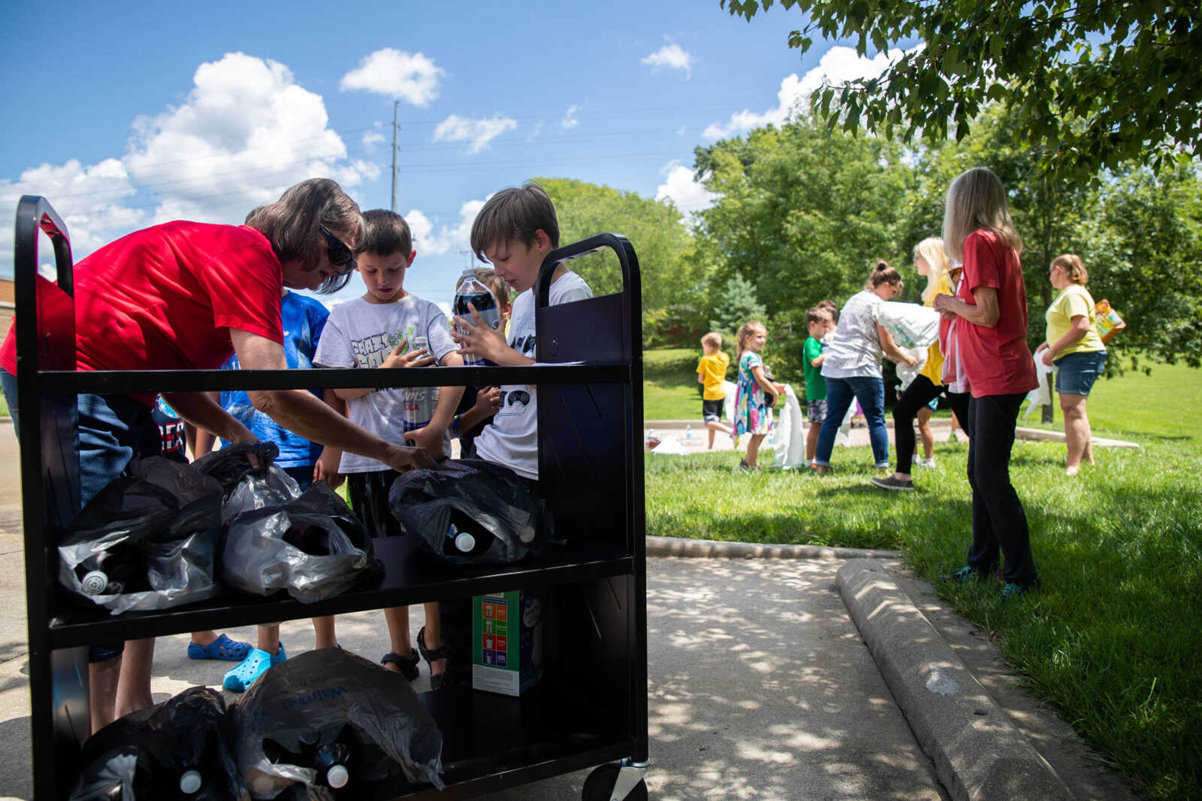 Becky Hicks hands kids two liter bottles of diet Coke as they prepare for an exploding science experiment.