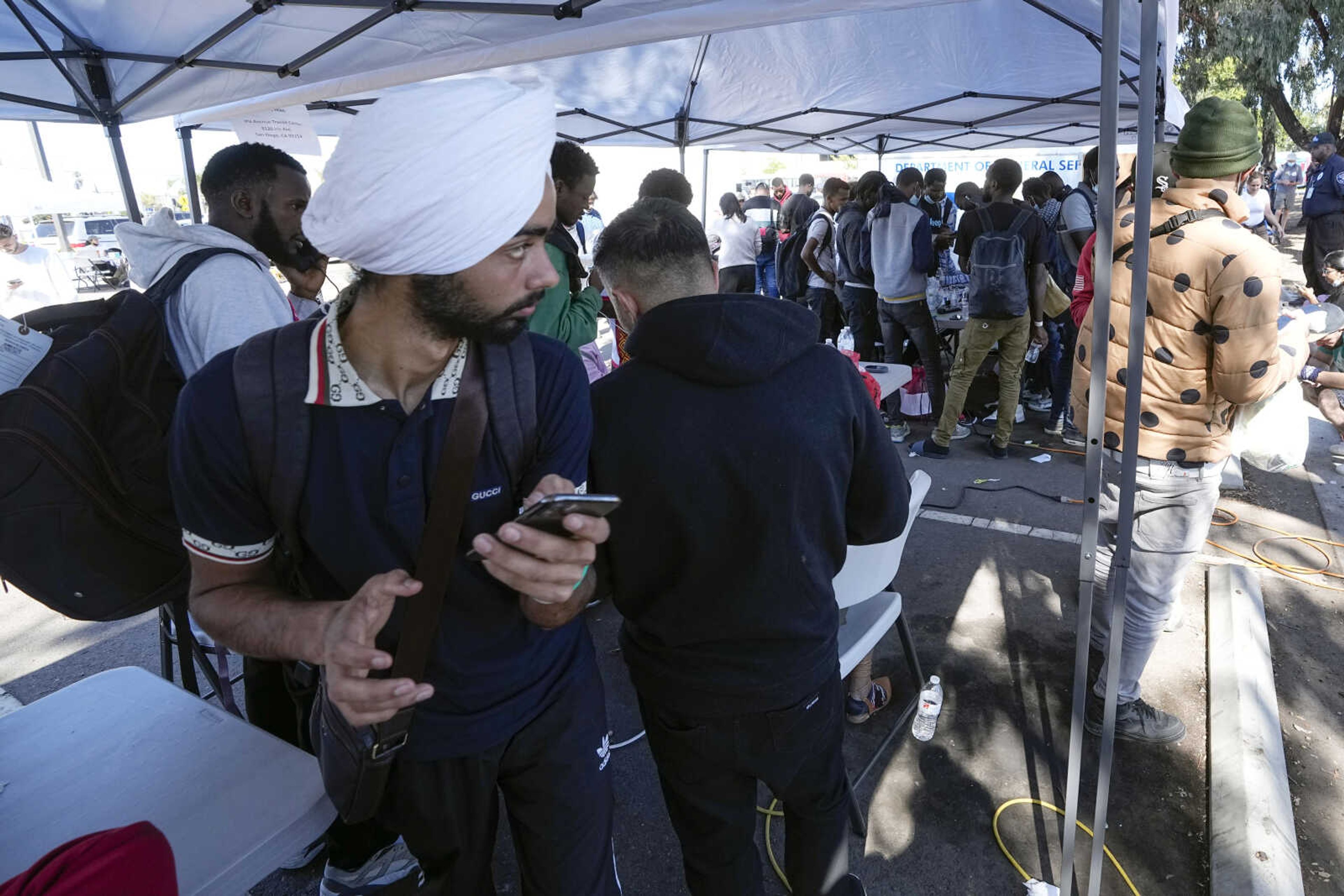 Migrants charge and use their phones in a parking lot set up to help people with travel plans, accommodation, food and shelter Friday in San Diego.