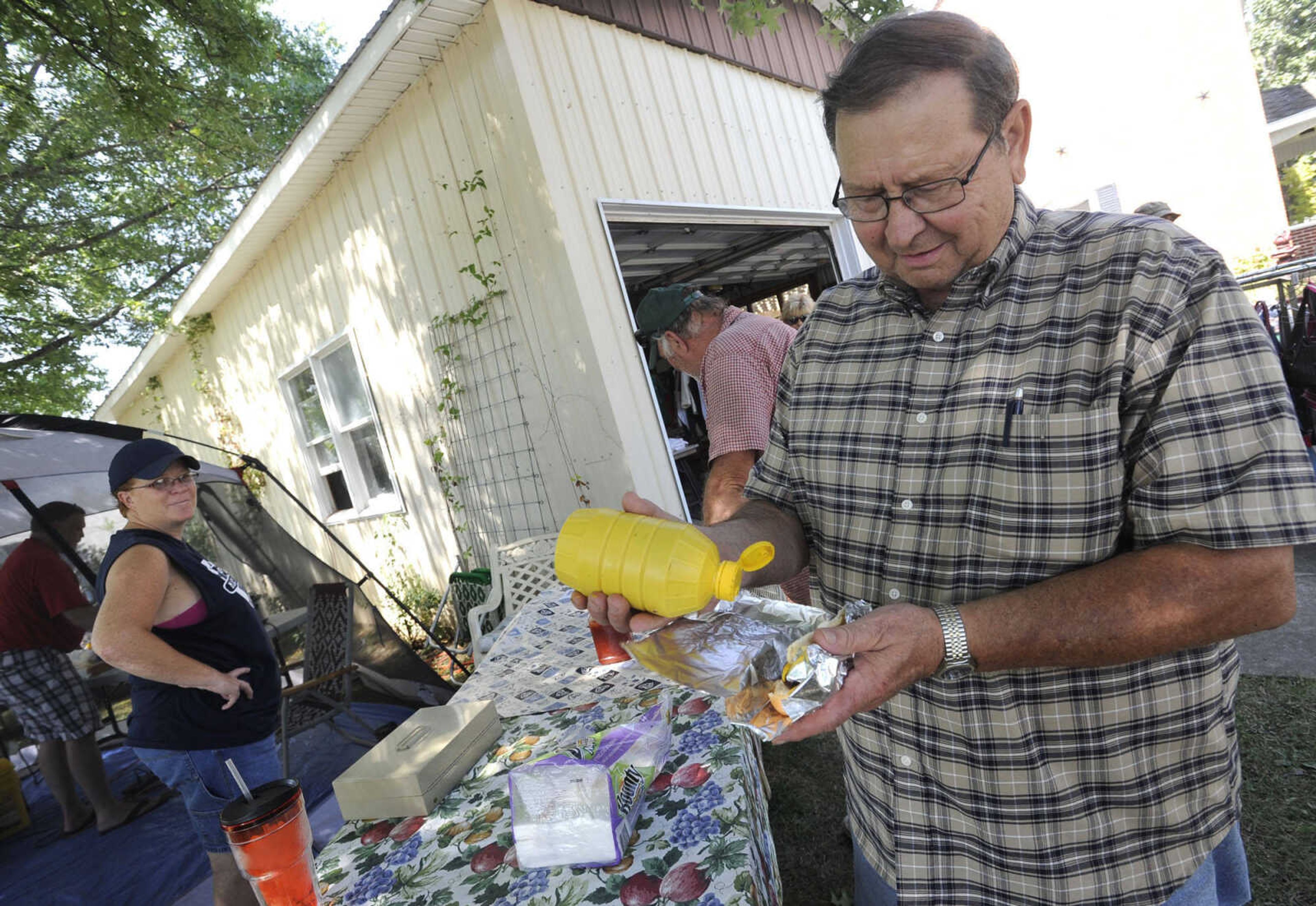 Allen Palisch of Effingham, Ill. bought a brat for lunch from Stacey Kinikin of Longtown, Mo. while shopping the Highway 61 Yard Sale Saturday, Aug. 31, 2013.