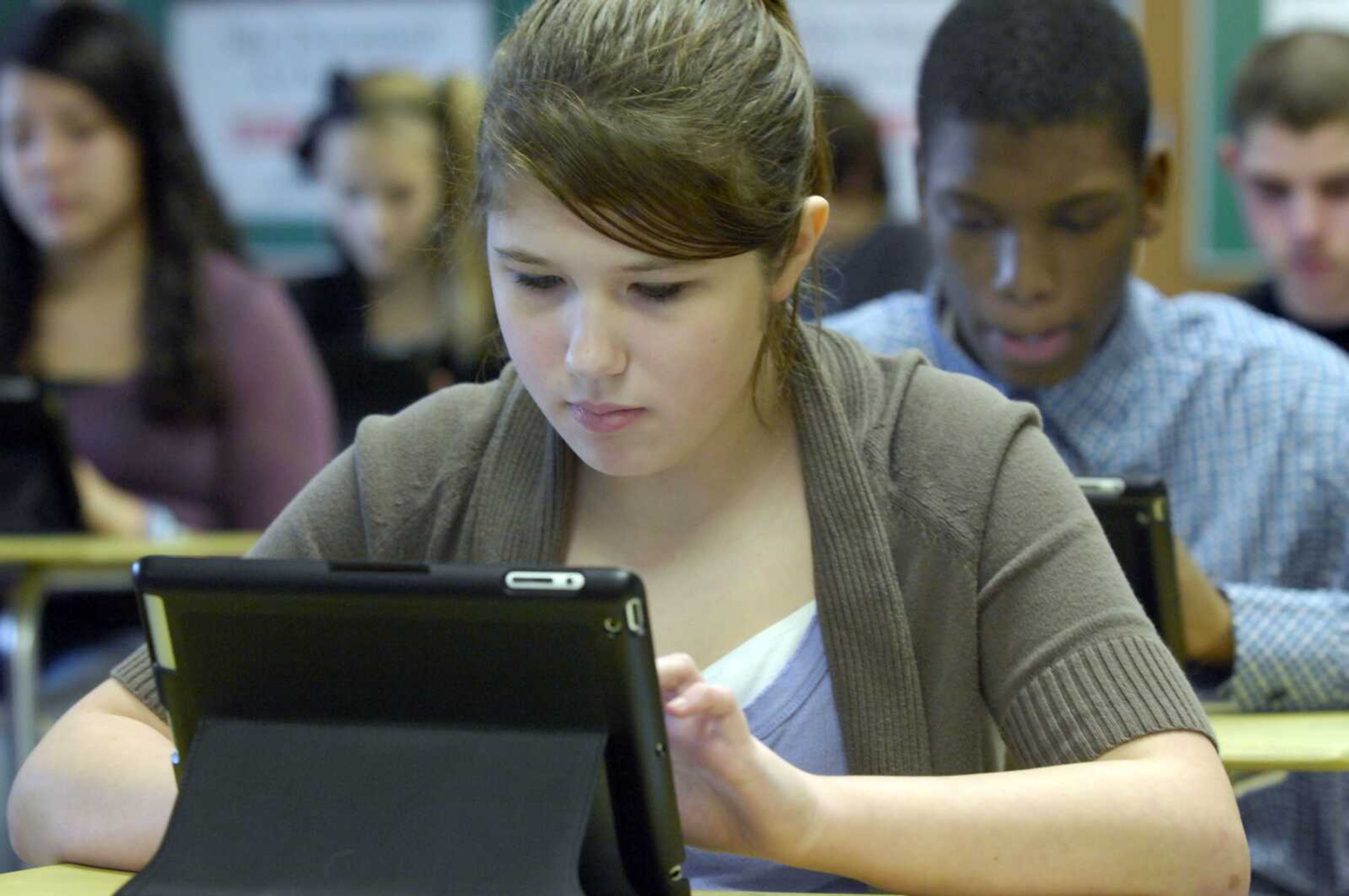 Eight grade students, including Jacquelyn De Guire, 13, left, and Lyrea Venzant, 14, use iPads on Wednesday to work with a folk tale they are reading in their enrichment English at Starbuck Middle School in Racine, Wis. Wednesday was named a national Digital Day, for schools to demonstrate the use of digital technology as the Obama administration challenges schools and companies to get every student digital textbooks within five years. (AP Photo/Journal Times, Mark Hertzberg)