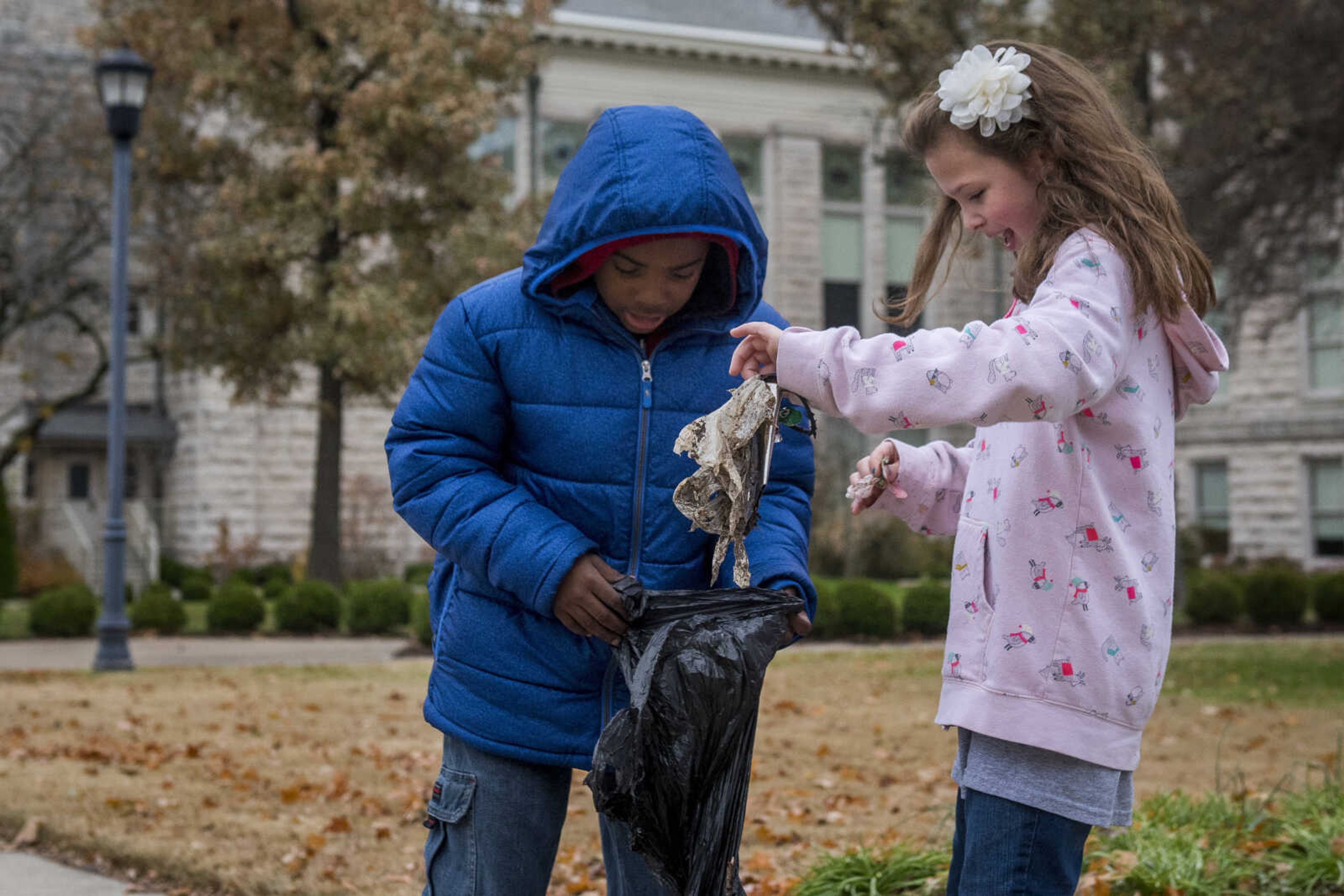 Jefferson Elementary students Lamonquez Vaughn holds a garbage bag for Joslin Kinder as they clean the Southeast Missouri State University campus as part of a beautification project Monday.